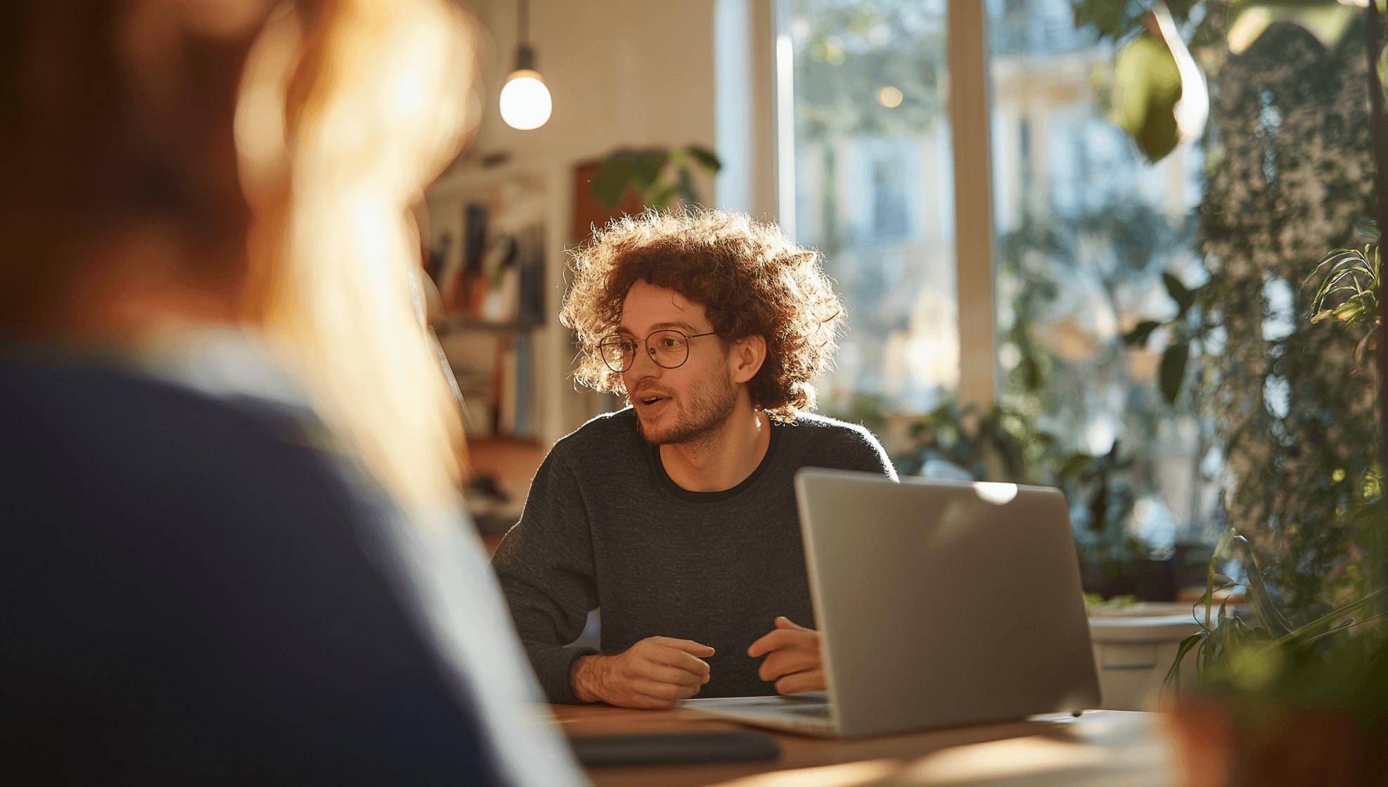 Image of two people working on laptops in a bright, modern workspace.