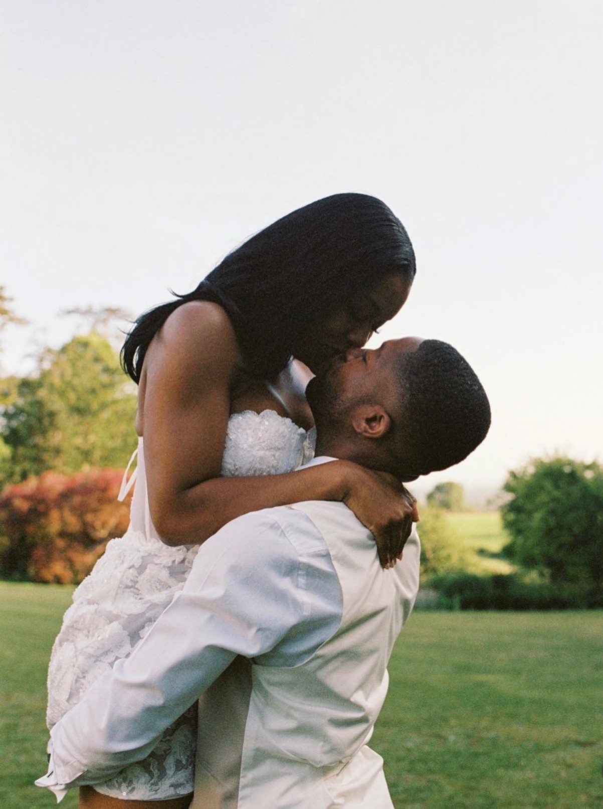 Newlyweds sharing a joyful kiss in a garden