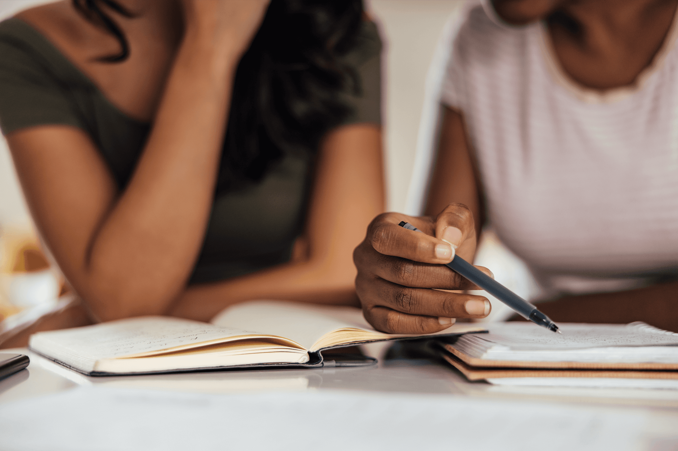Two women discussing over a diary with one holding a pen in her hand