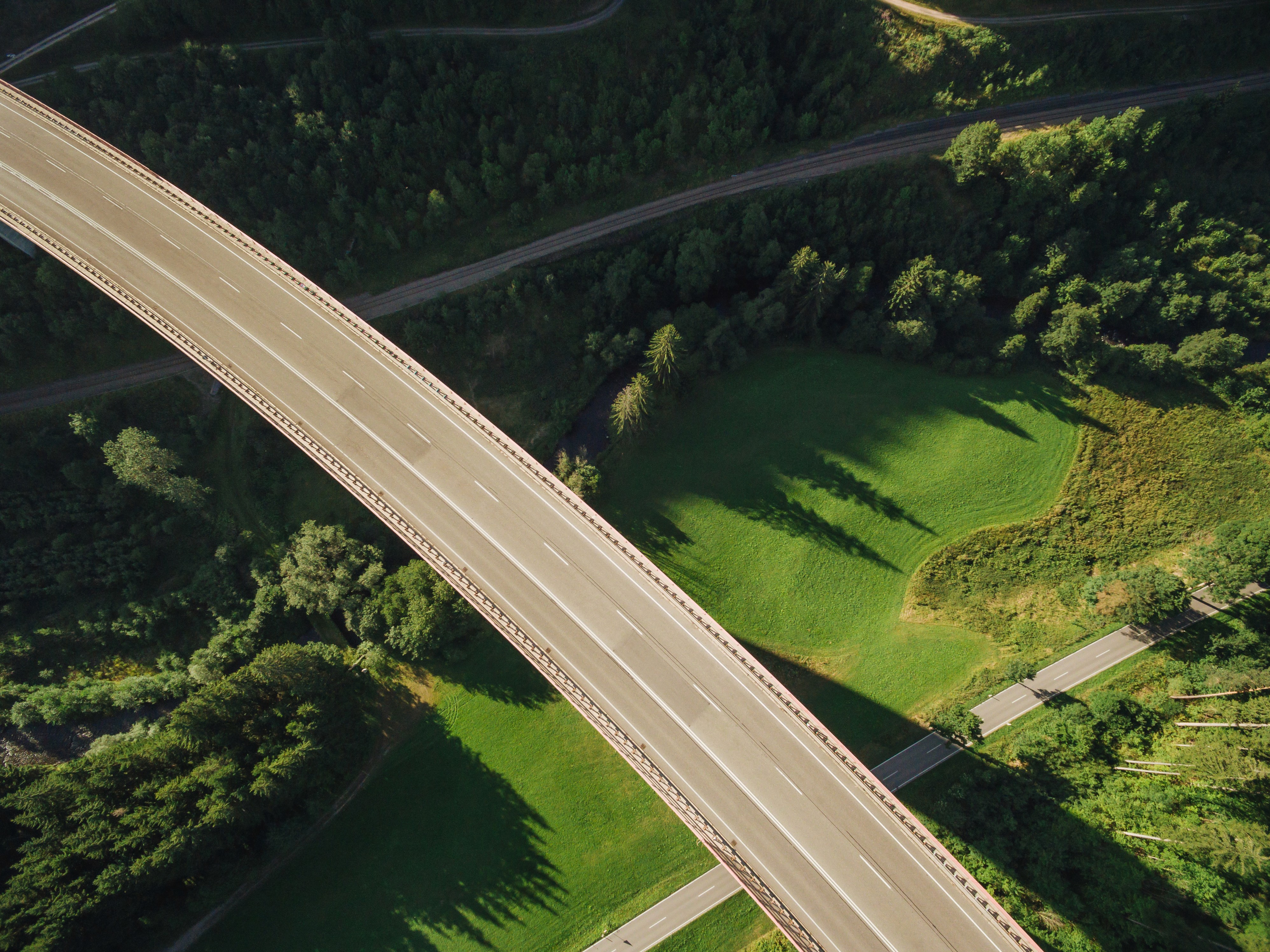 Birds eye view of a highway lane going through a green countryside.