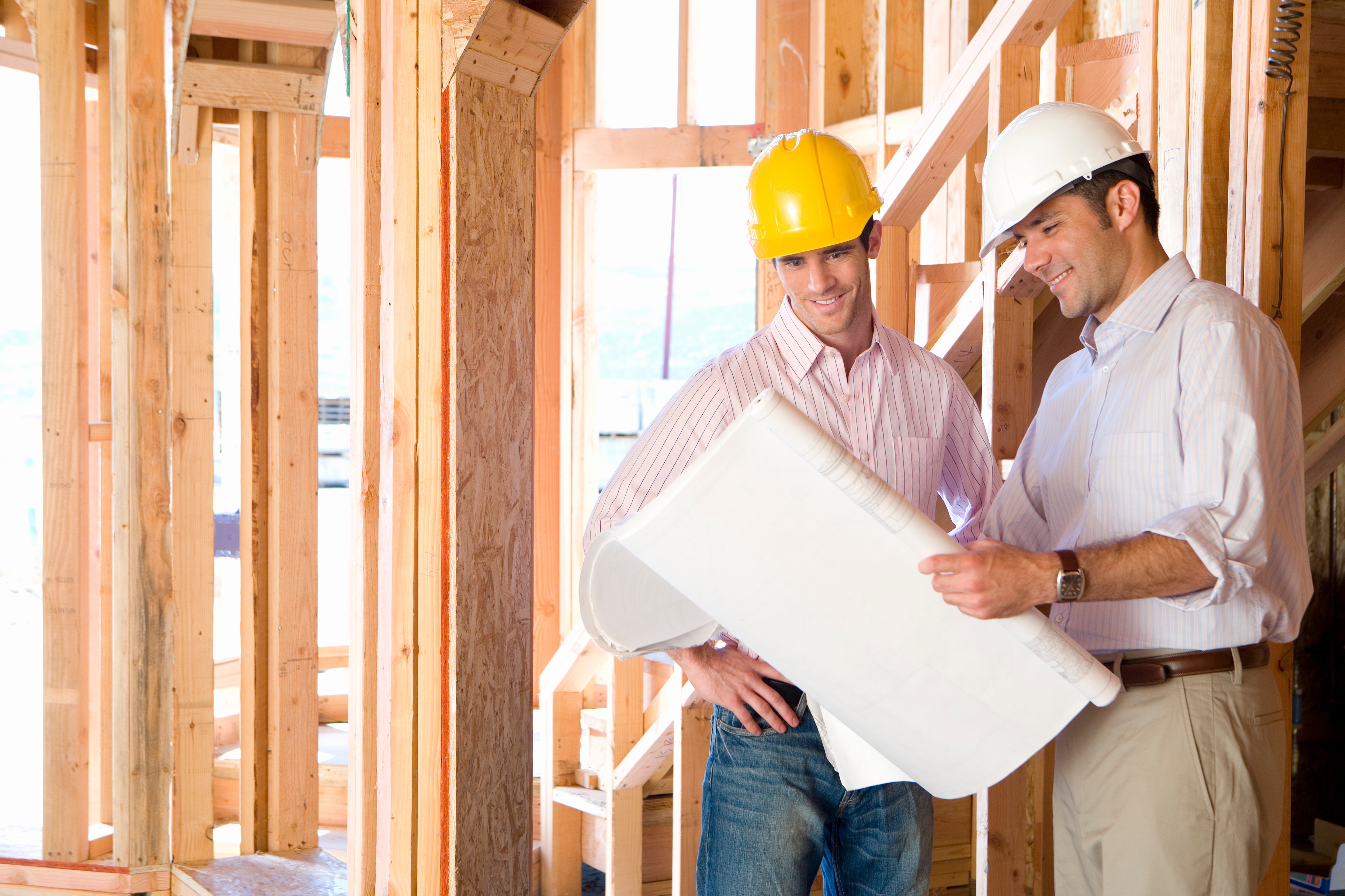 Construction workers reviewing blueprints on active residential construction job site