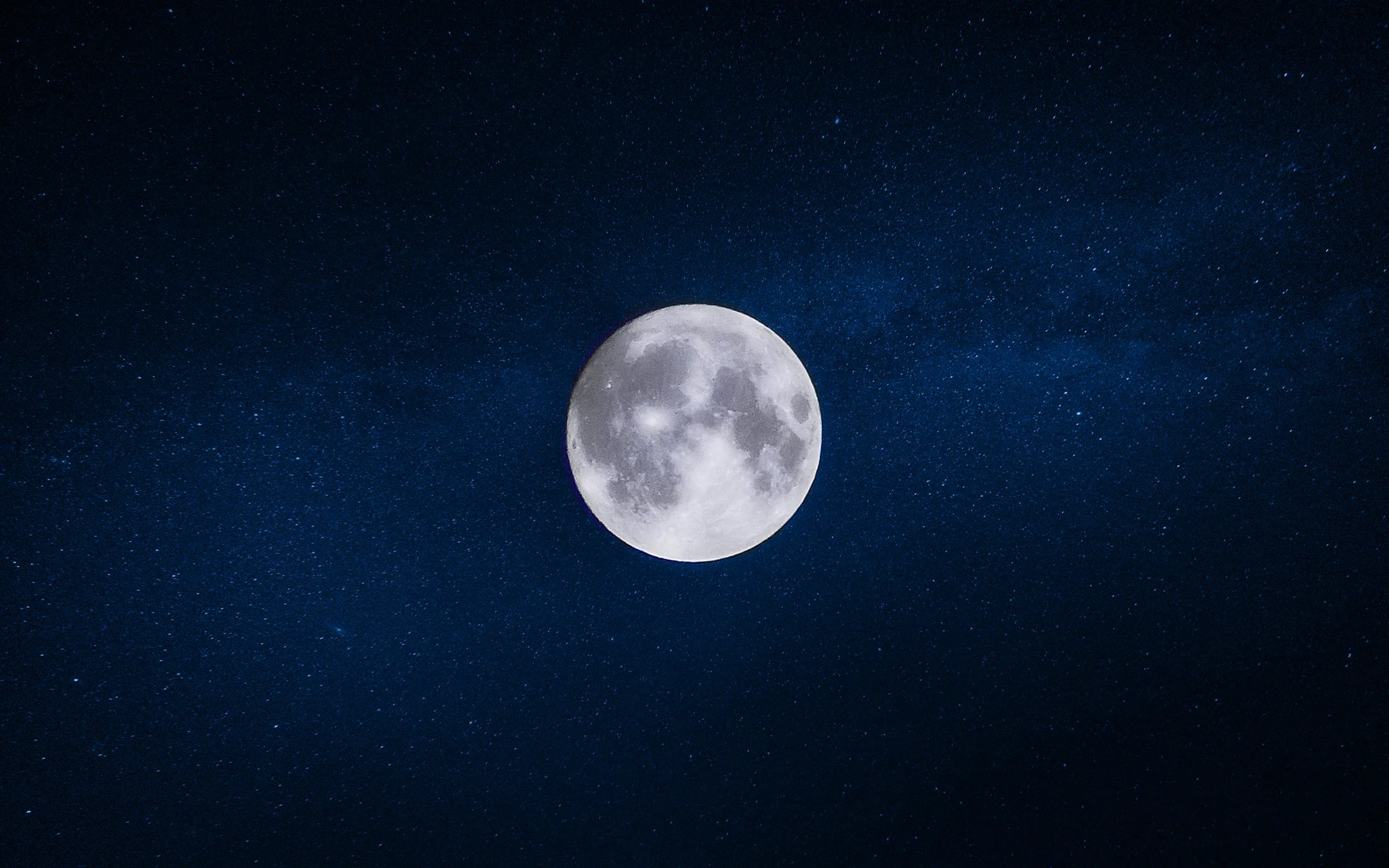 Full moon glowing brightly against a dark night sky filled with stars.