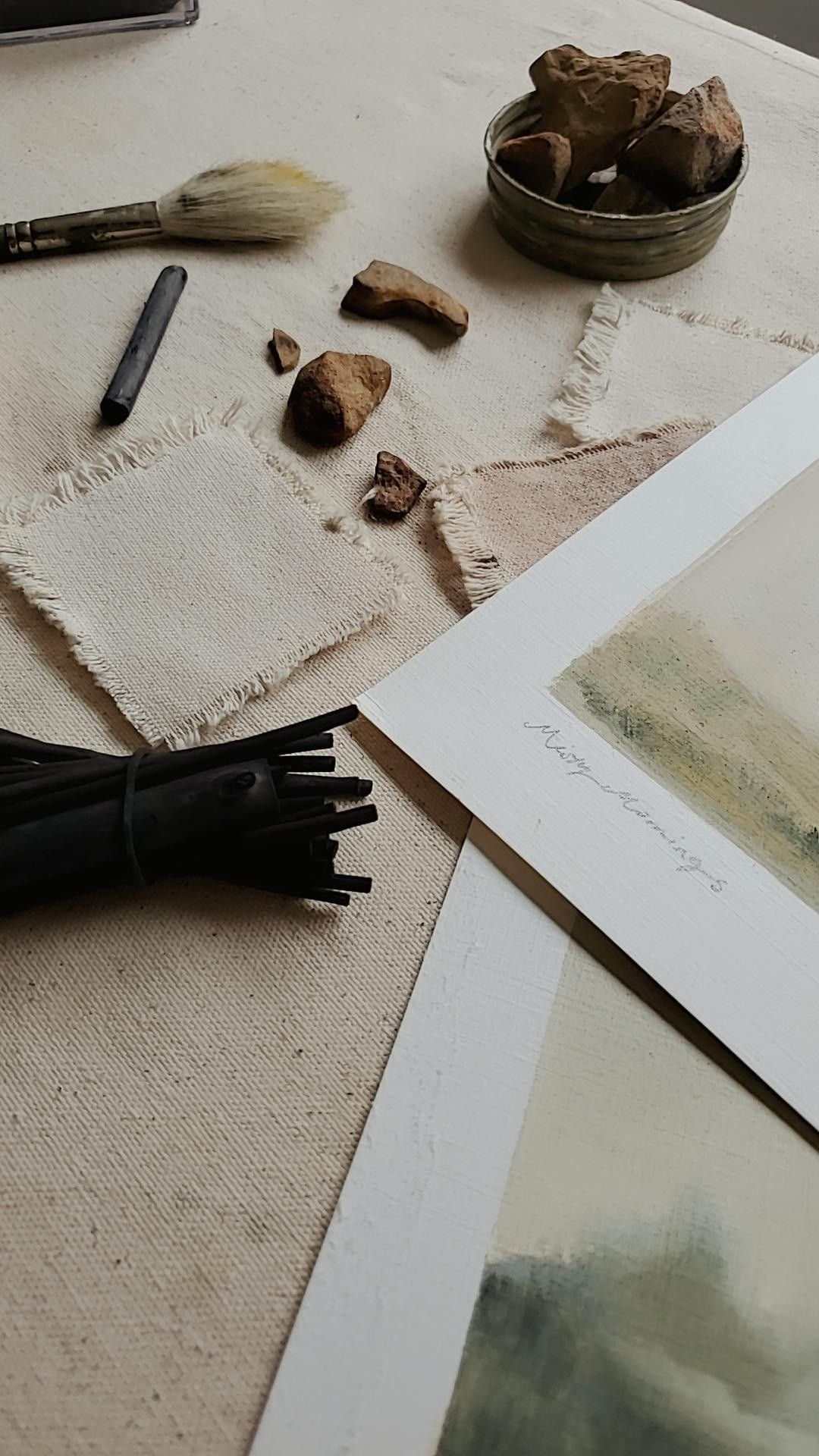 A person in an apron uses a wooden peel to place a freshly baked loaf of artisan bread into a rustic, wood-fired oven, with a flickering fire visible inside, set against the backdrop of a sunlit kitchen.