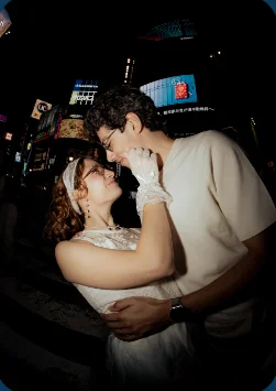 Couple photographed at night under Tokyo signs