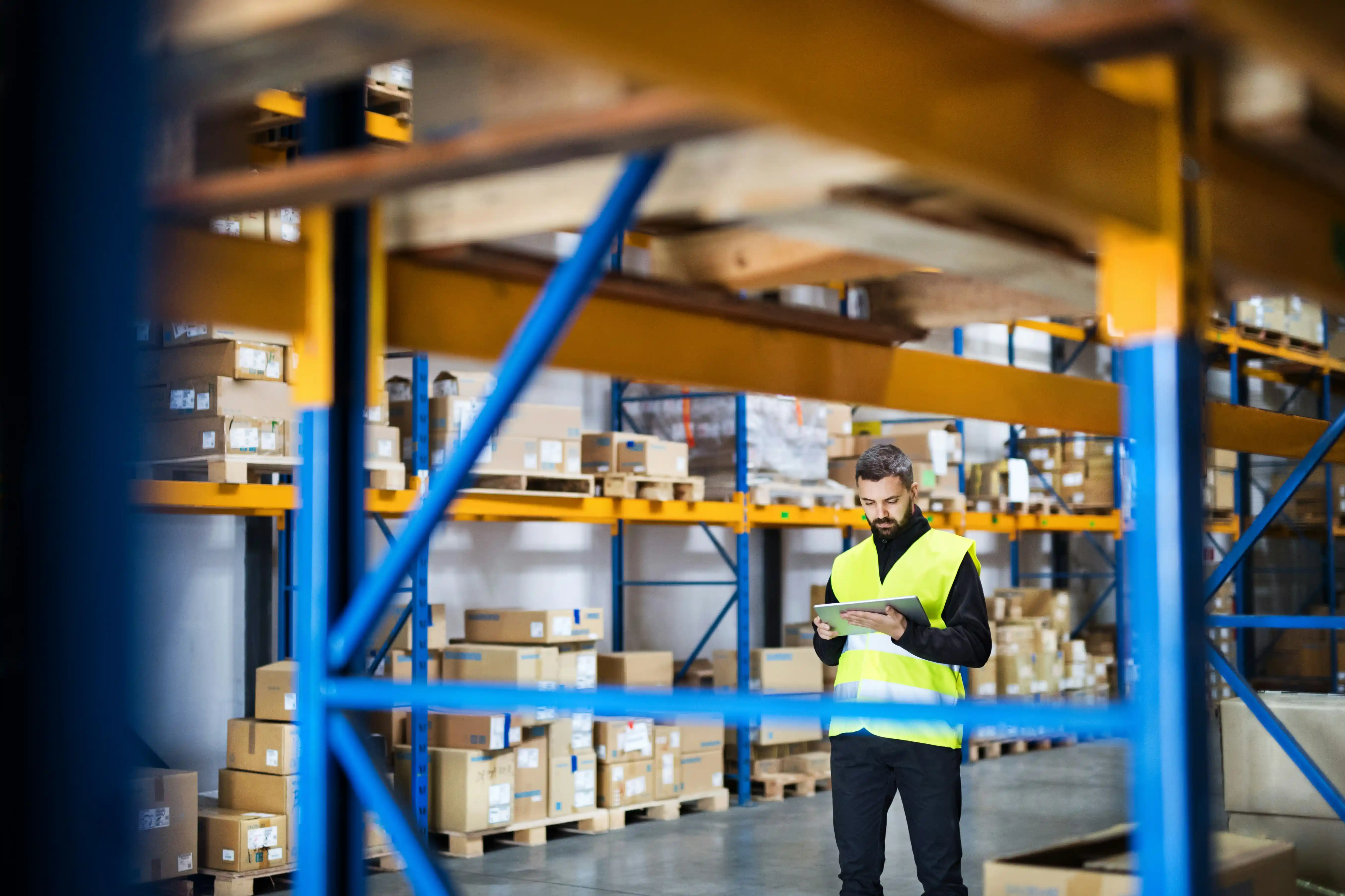 warehouse worker in green high-vis jacket manages warehouse stock