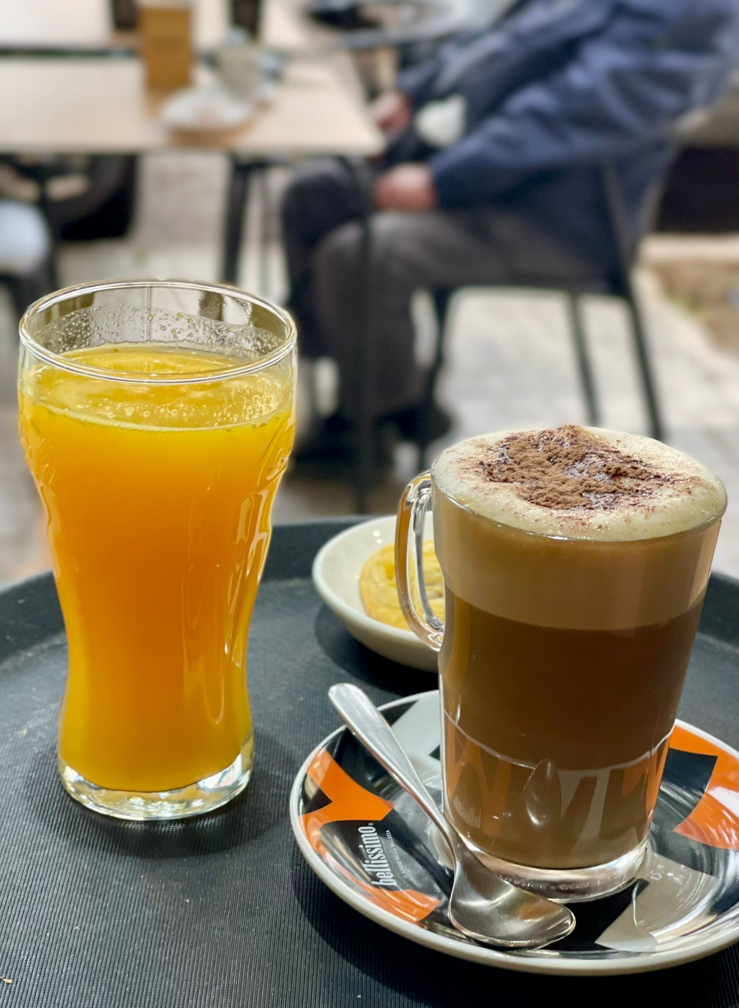 Wooden outdoor table set with multiple plates of food, including dips, salads, potatoes with cheese, and glasses of water, with hands reaching in to eat.