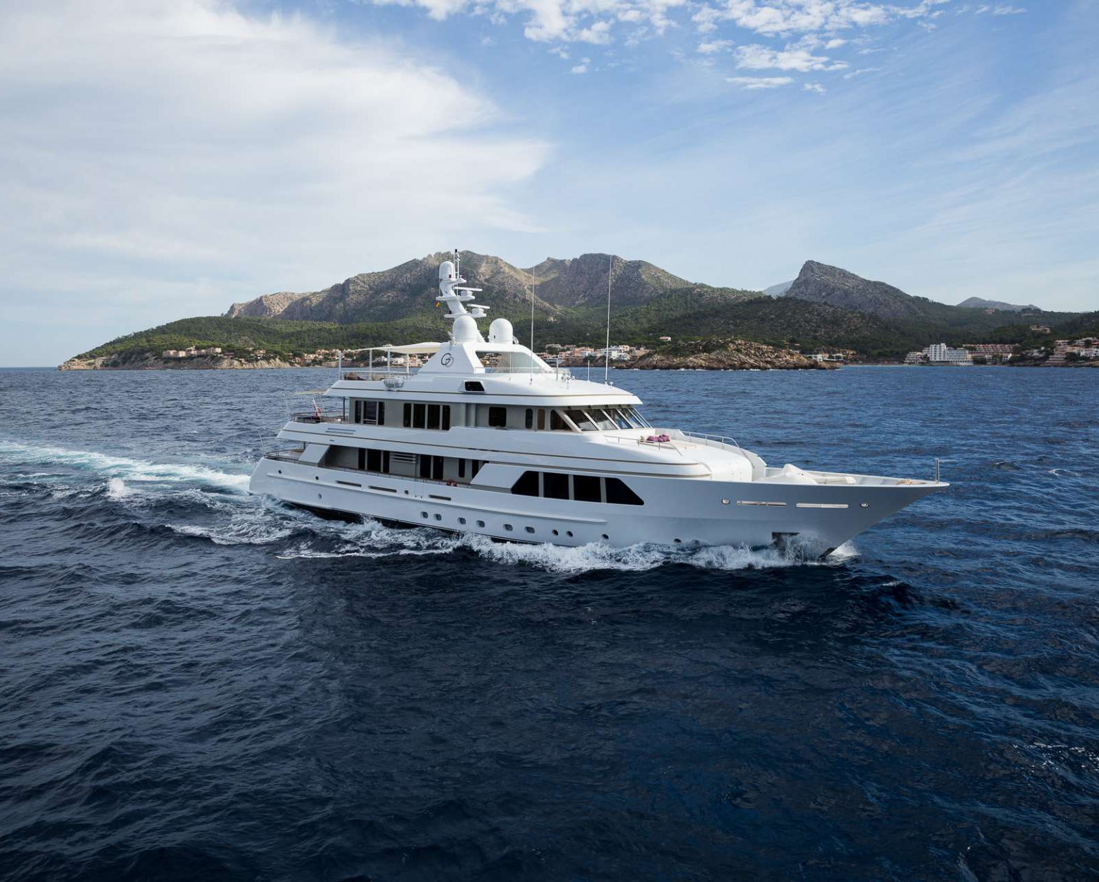 Aerial view of a boat navigating through deep blue waters, creating ripples in its wake.