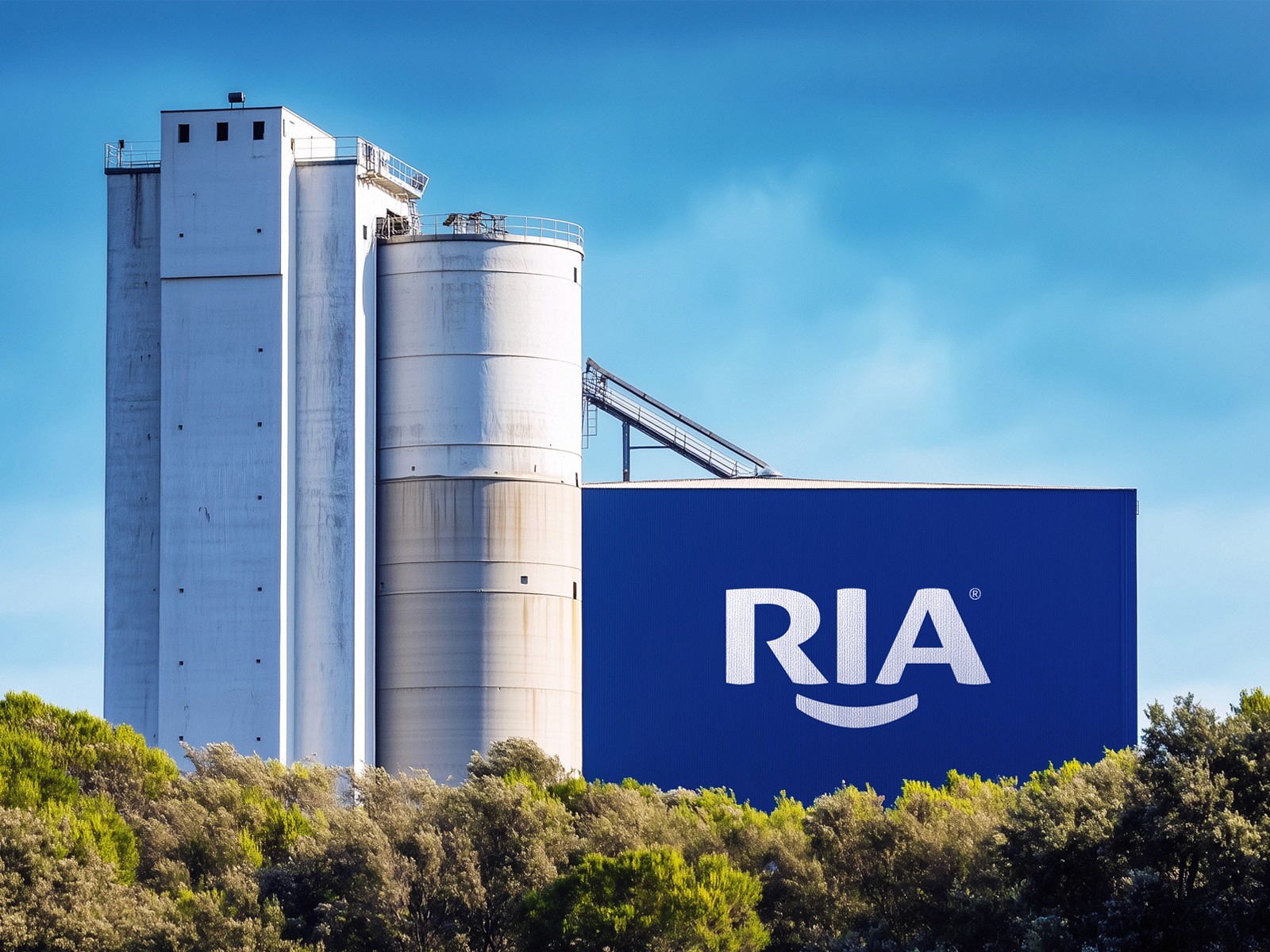 Large RIA logo displayed on the side of an industrial facility surrounded by greenery.