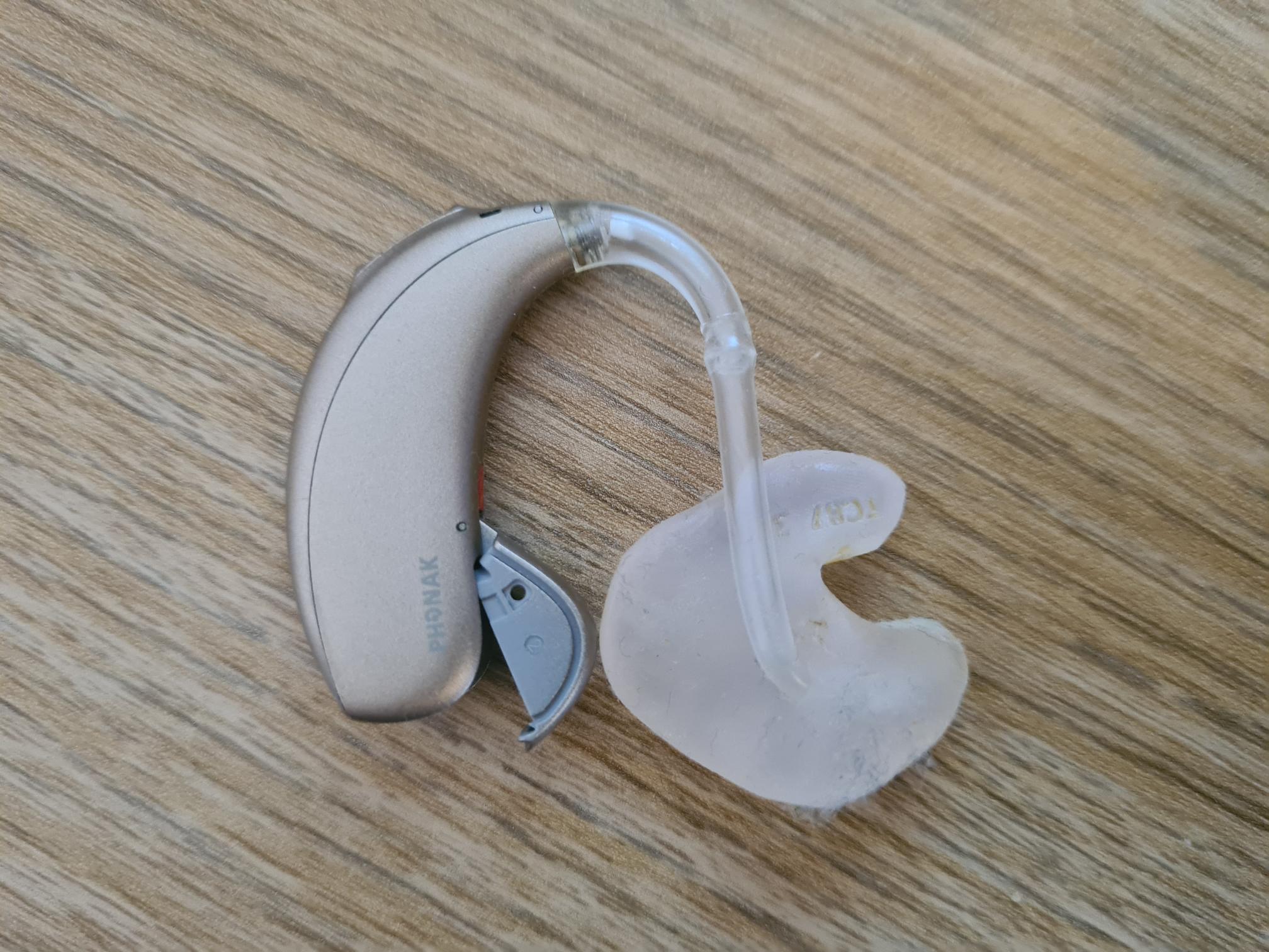 A hearing aid photographed on a wooden surface