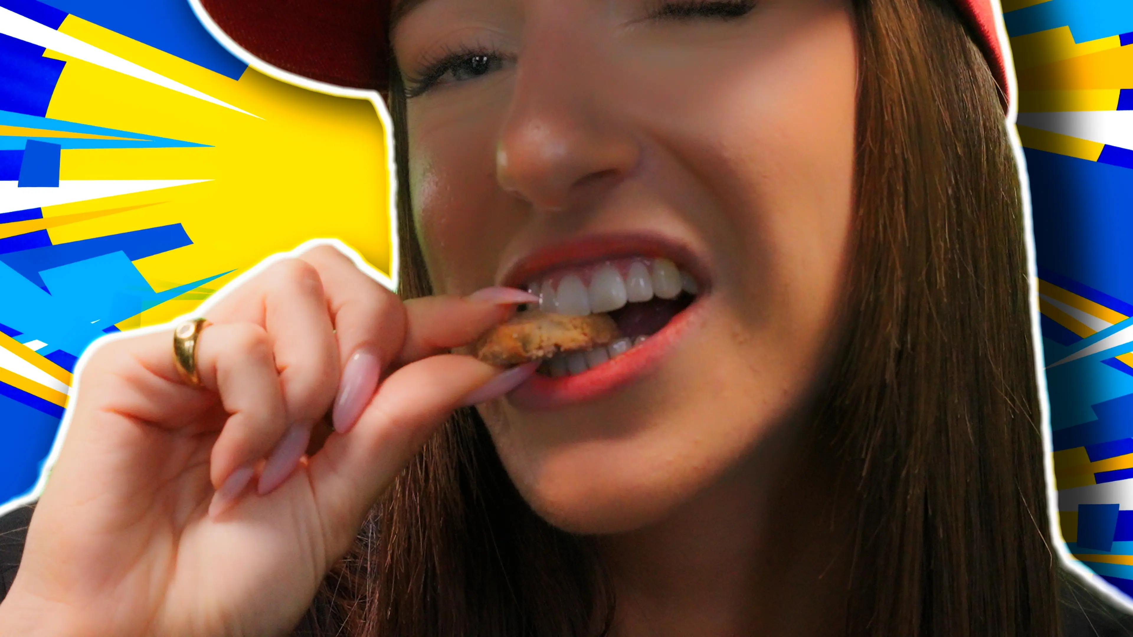 A person wearing a red cap takes a bite of a cookie against a vibrant background with blue and yellow geometric patterns, adding a dynamic pop of color.