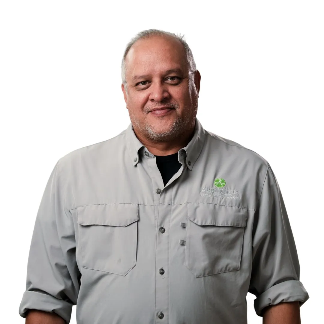 Man in gray shirt with green logo smiles.