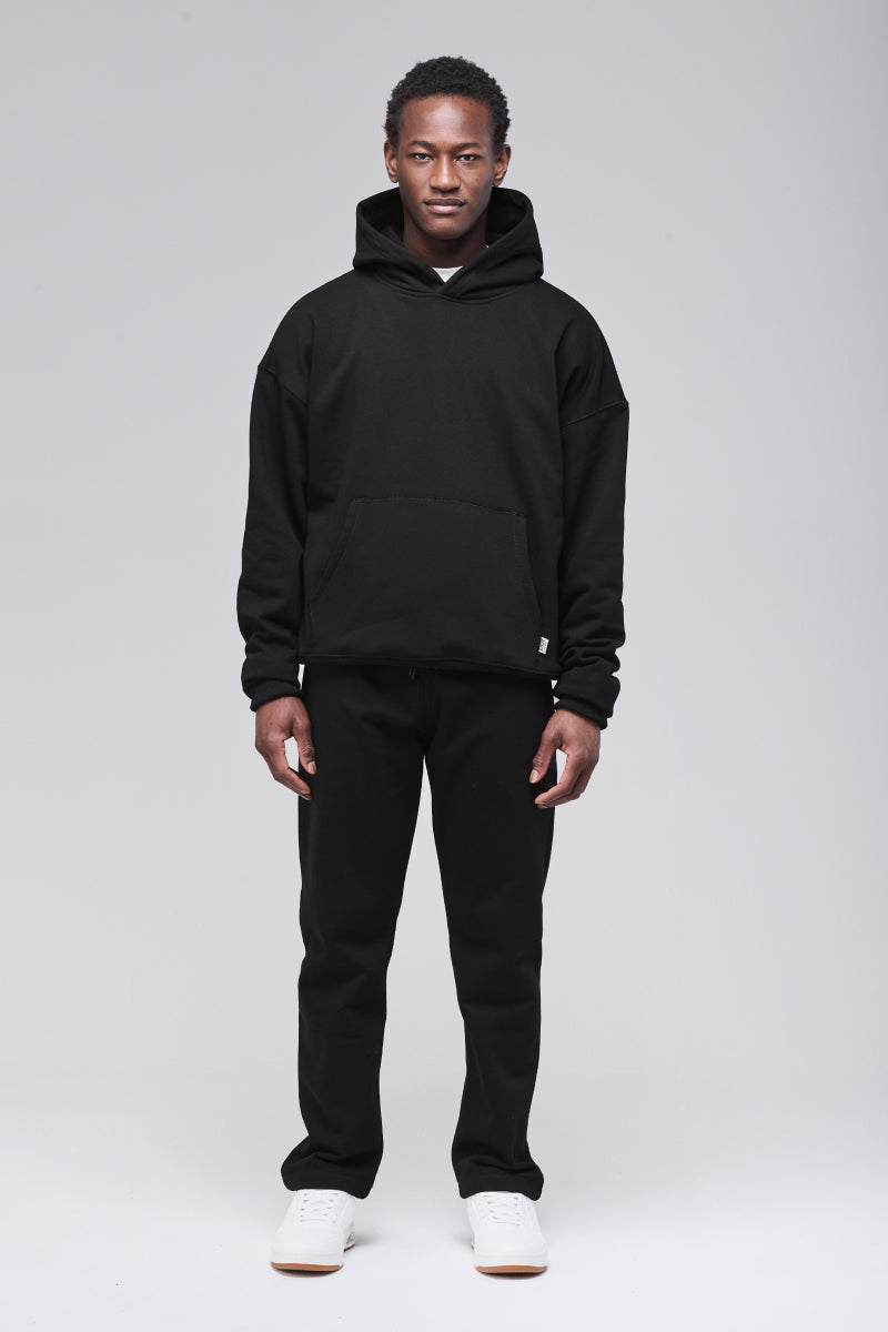 Male model wearing black boxy hoodie, side view