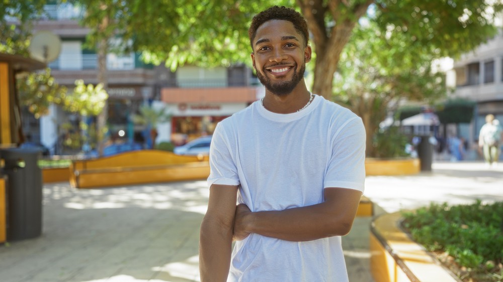 Jeune homme souriant dans un parc, représentant la tranquillité d'esprit offerte par l'assurance vie temporaire 100 ans.