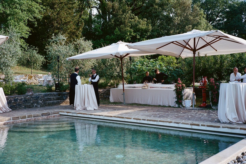 Poolside wedding reception with cocktail tables and umbrellas at a countryside estate