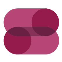 A smiling person with curly hair sits at a desk, looking at a laptop against a dark background.