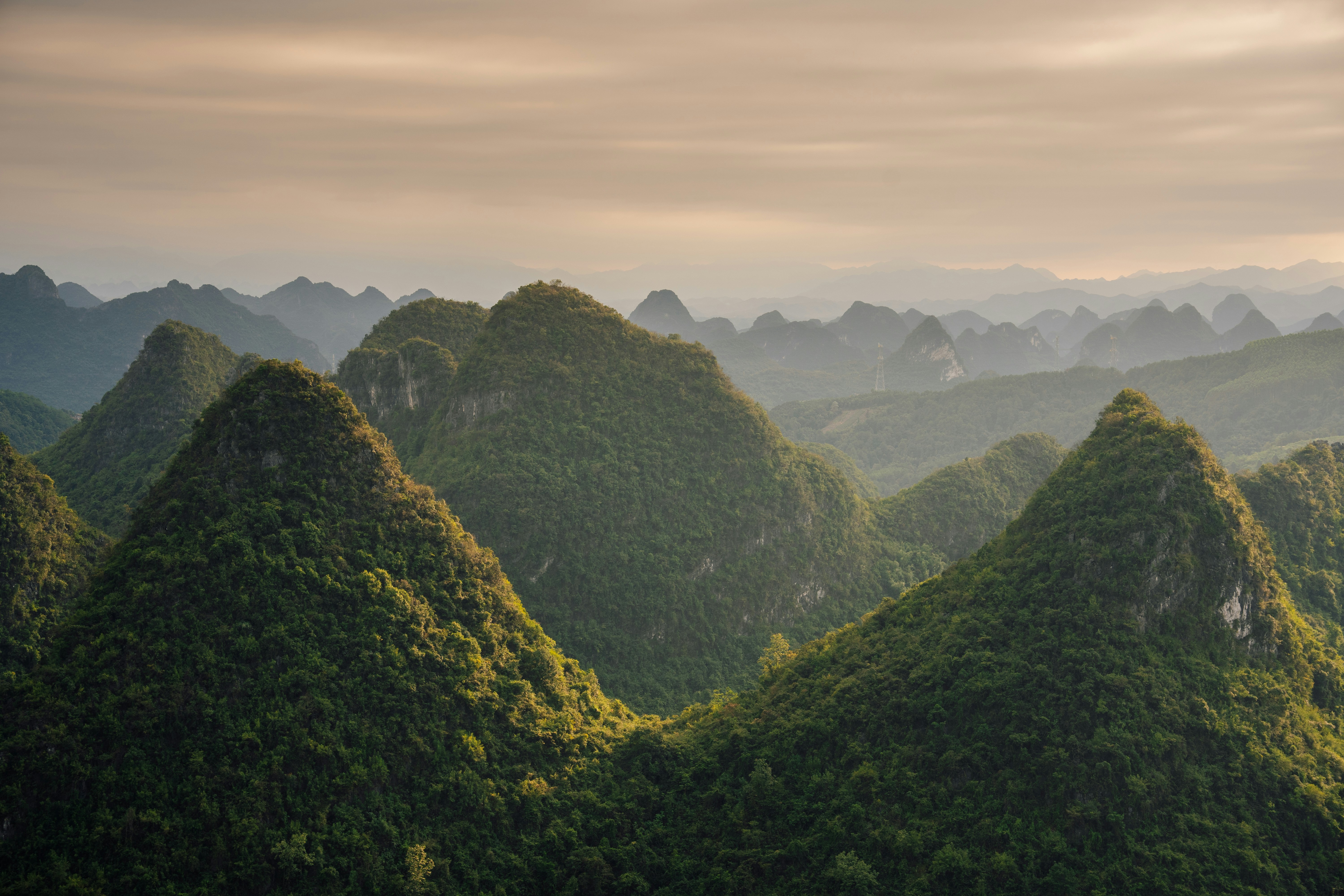 Lush green conical mountains under a hazy sky