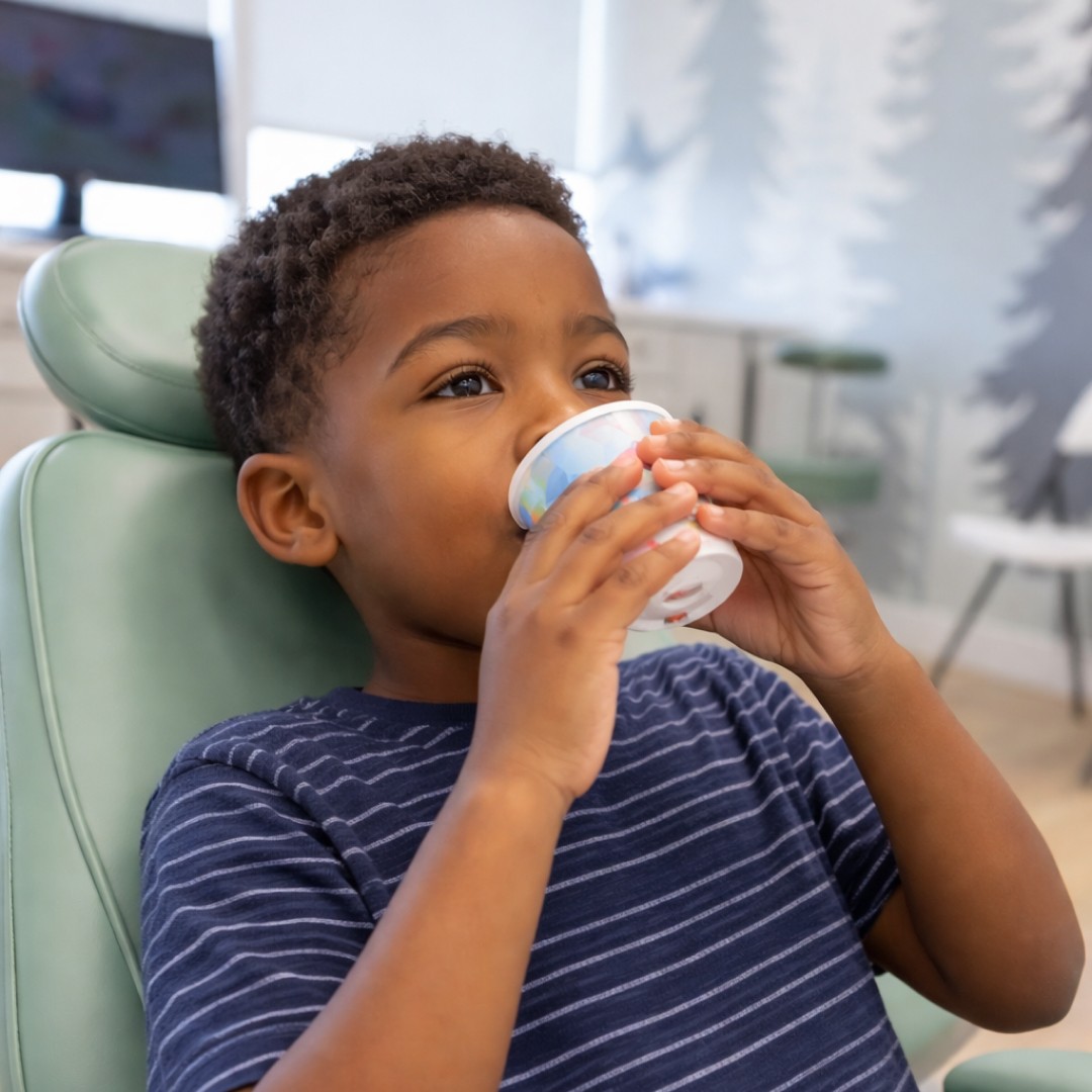 Child comfortably drinking a sedative medication before a dental procedure to ensure a stress-free experience.
