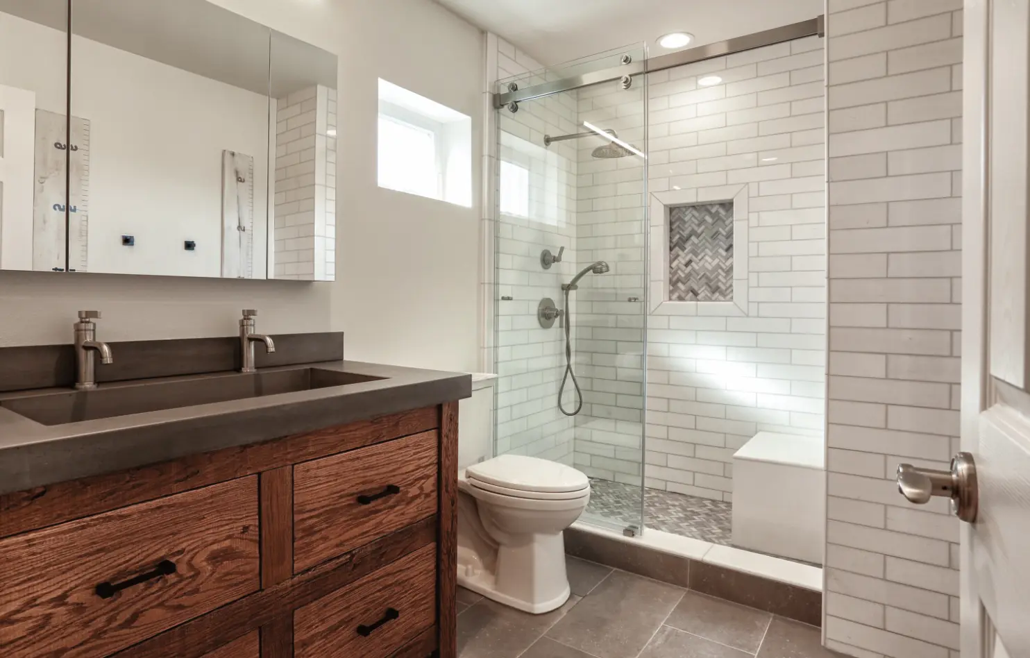 Rustic Farmhouse gues bathroom with double vanity, concret countertop, stain pine vanity cabinets, tile shower enclosure. Photo by Chris Darnall.