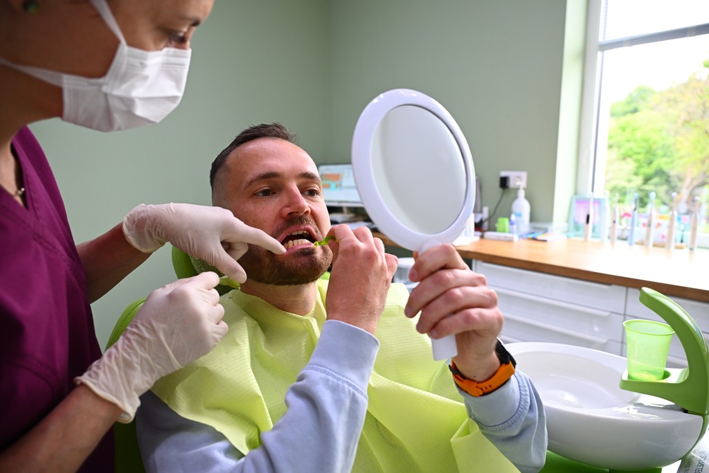 Dentálna hygienička vysvetluje pacientovi použitie medzizubných kefiek