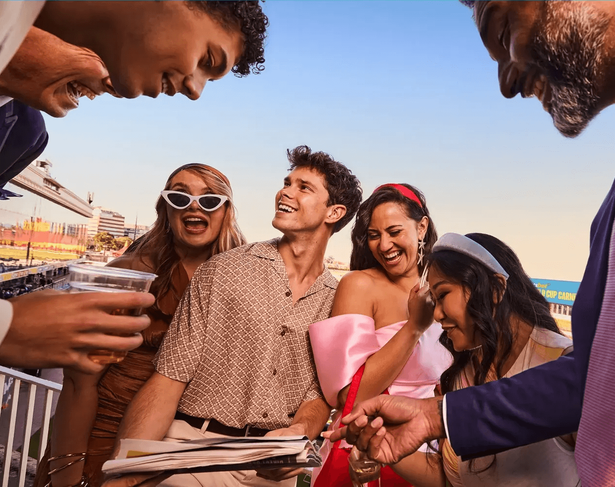 A woman with red hair wears a lavender coat and a white sweater, accessorized with a gray scarf. She has a calm expression against a neutral background.