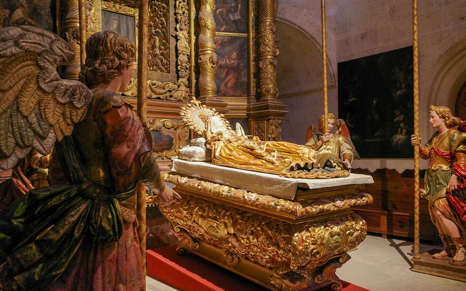Estatuas religiosas en la Catedral de Palma que representan ángeles alrededor de un altar dorado.