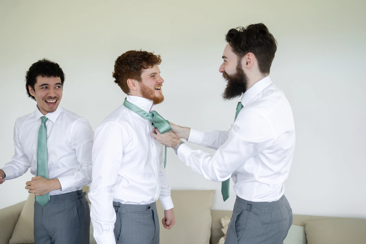 Best man fixing groom's green tie