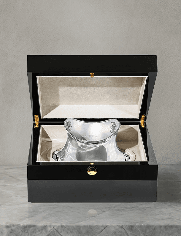 The completed, highly polished silver neck collar displayed inside an opened luxury black lacquered box with soft cream velvet lining, labeled "04 Presentation."