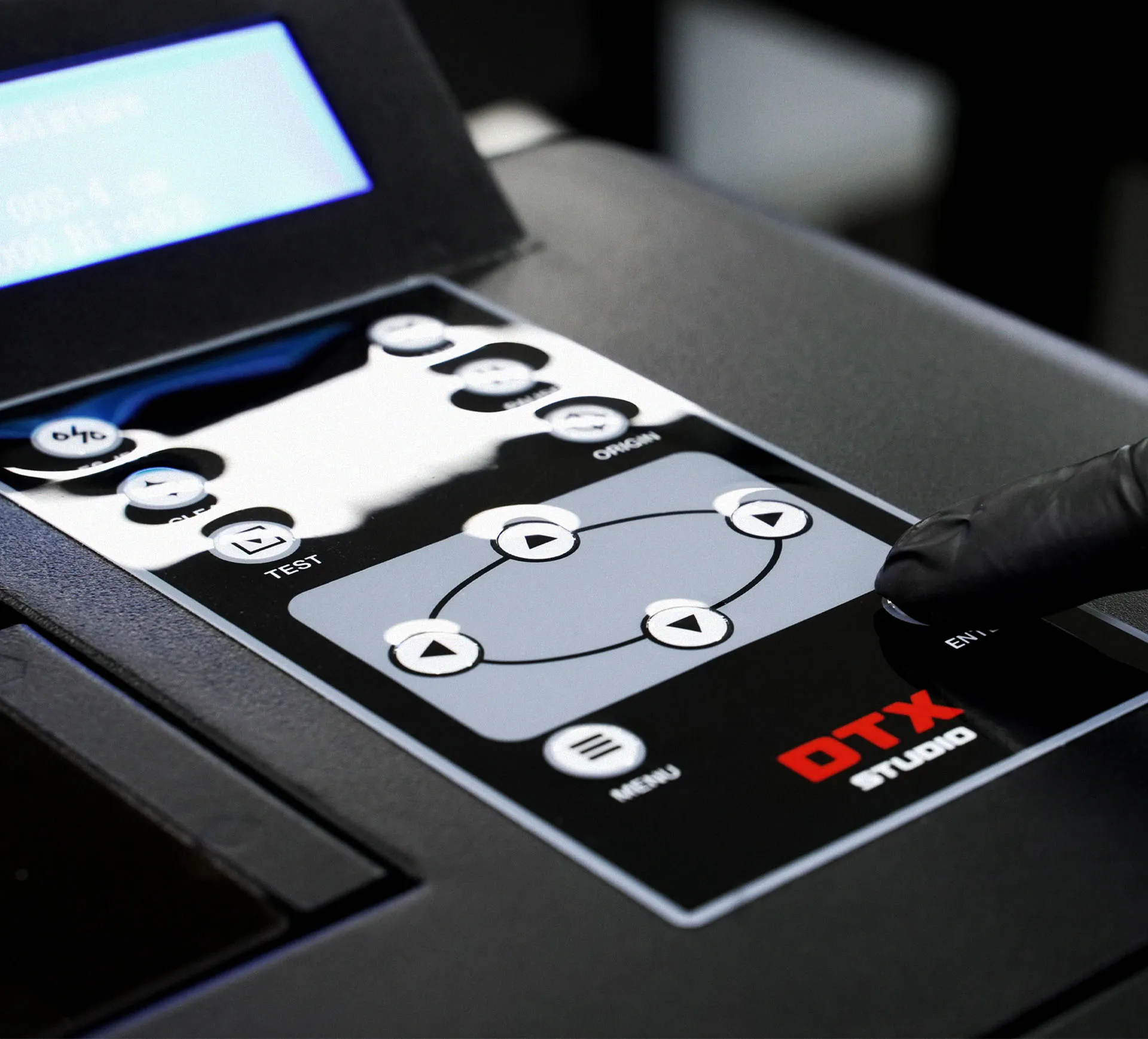 A close-up of a gloved hand operating the physical control panel of the Gravity Pro DTF printer to activate the automatic fill-up system with a single touch.