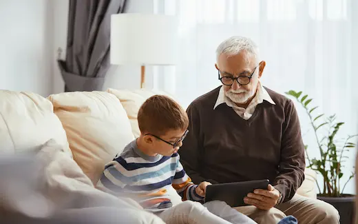 A photo of a grandfather and grandson looking at a smart tablet together