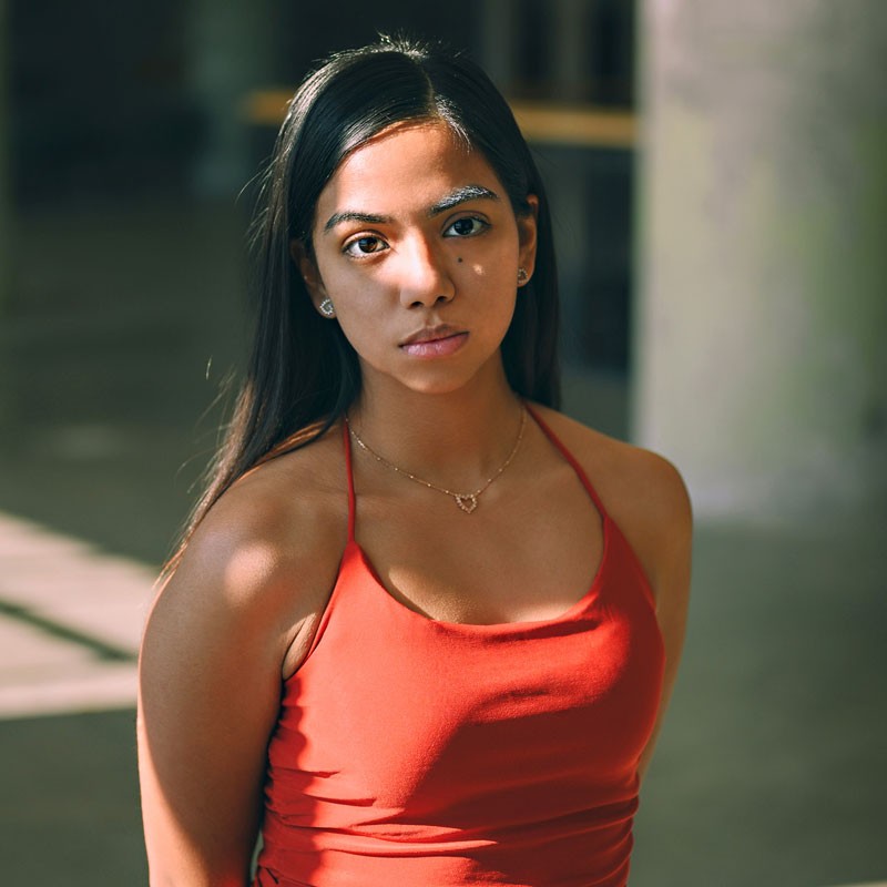 Fotografía de una mujer joven de piel morena y cabello largo negro, con expresión reflexiva; representa el perfil de una madre de familia interesada en servicios de salud mental y bienestar emocional para fortalecer sus vínculos personales.