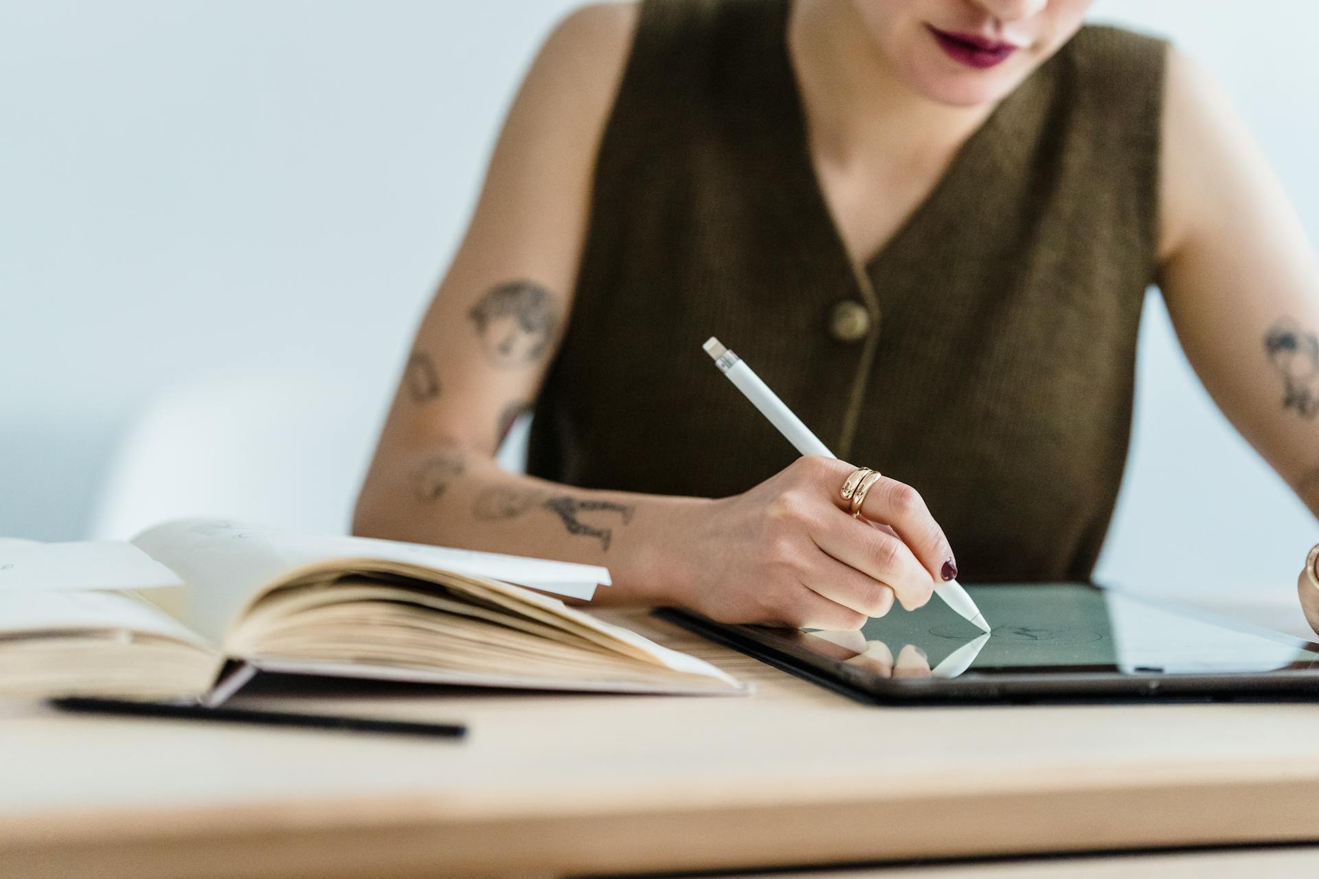 A woman wearing an armless shirt darwing on an ipad