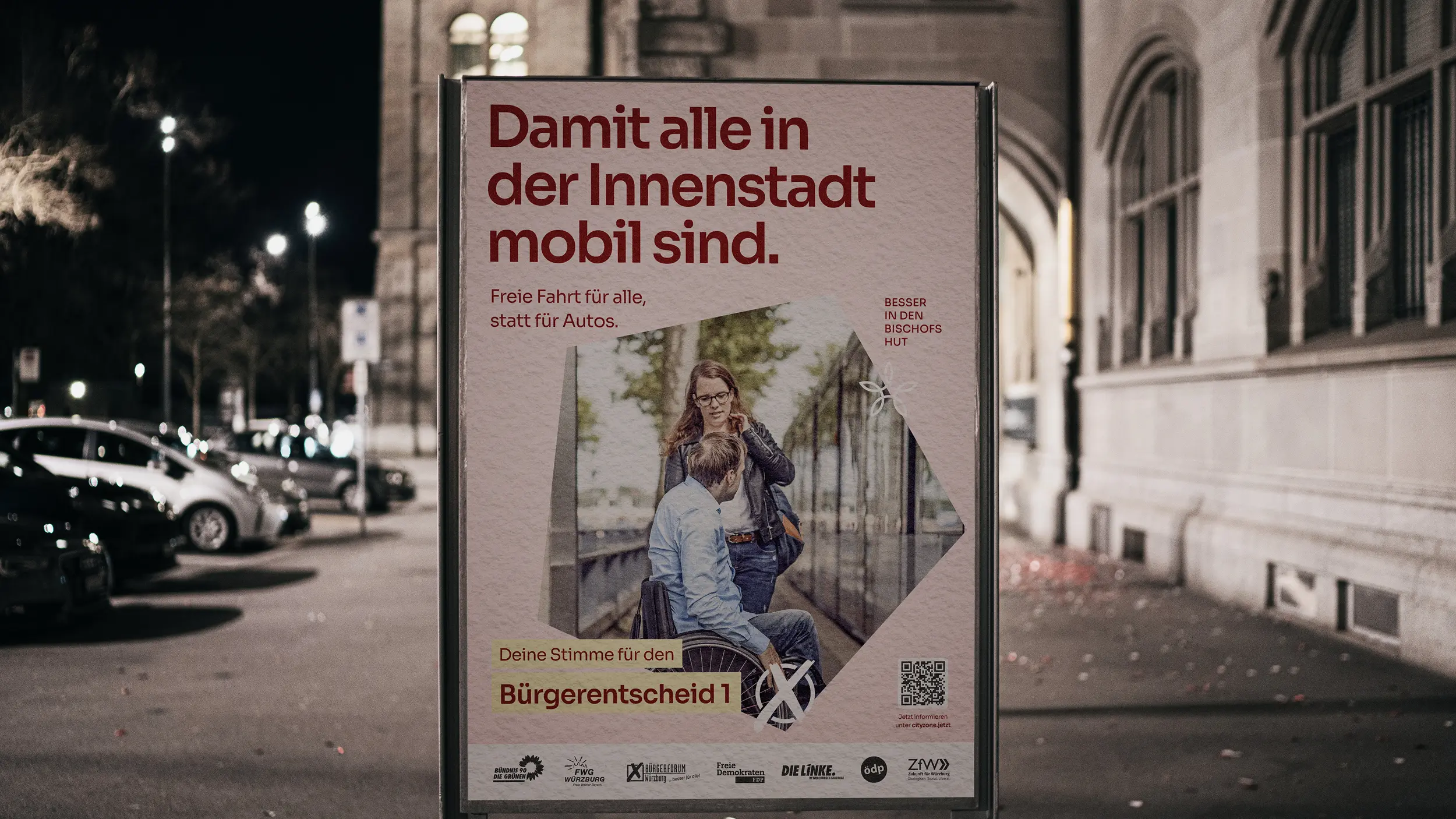 Nachtaufnahme eines Plakats „Damit alle in der Innenstadt mobil sind“ mit Frau und Rollstuhlfahrer im Gespräch.