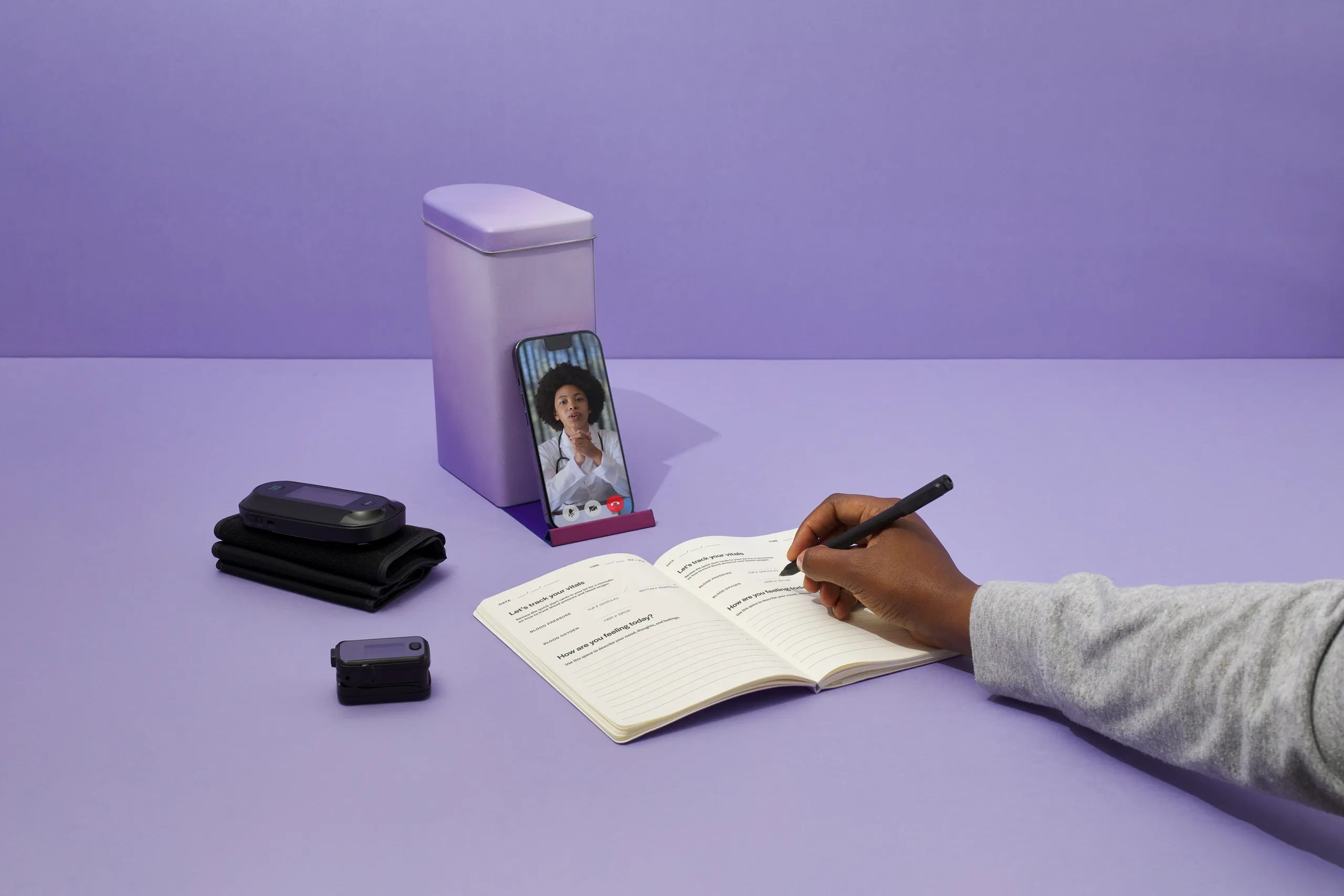 Person writing in the Spora Health Momma’s Kit guide beside maternal health monitoring devices