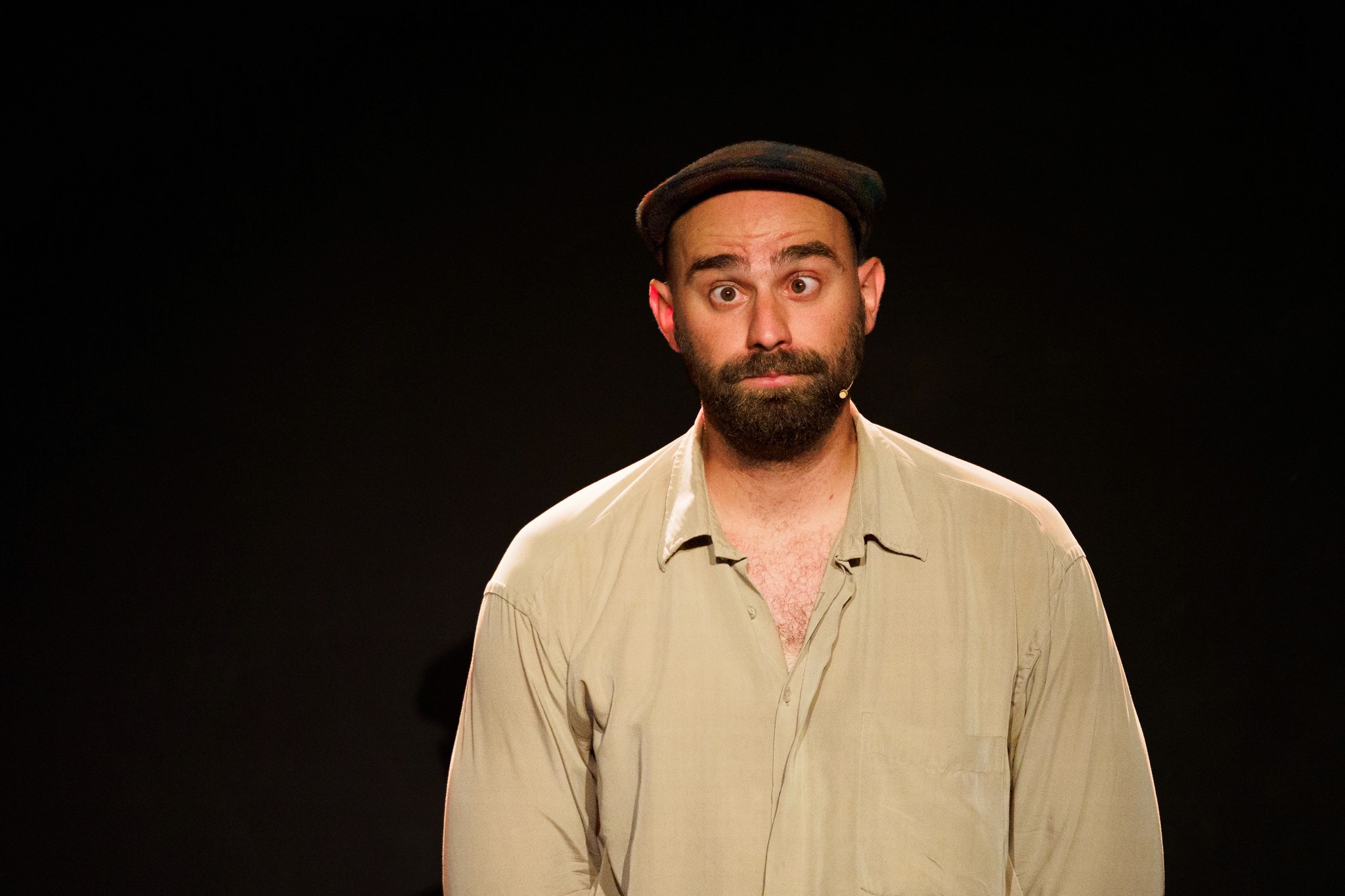 comédien sur scene avec une casquette louchant