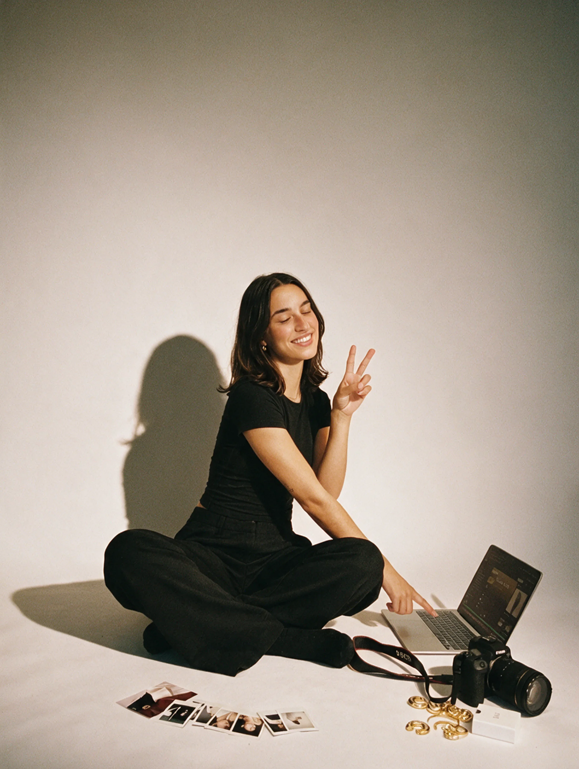 Amelia sitting cross-legged on the studio floor, smiling with a peace sign