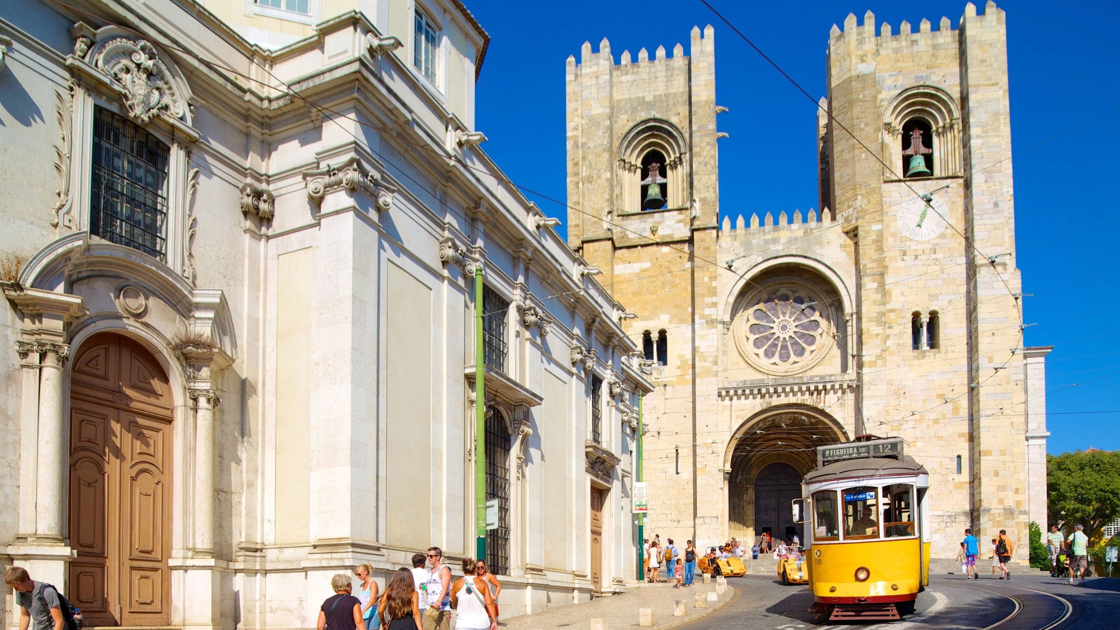 Vintage yellow tram 12 passing in front of Lisbon Cathedral