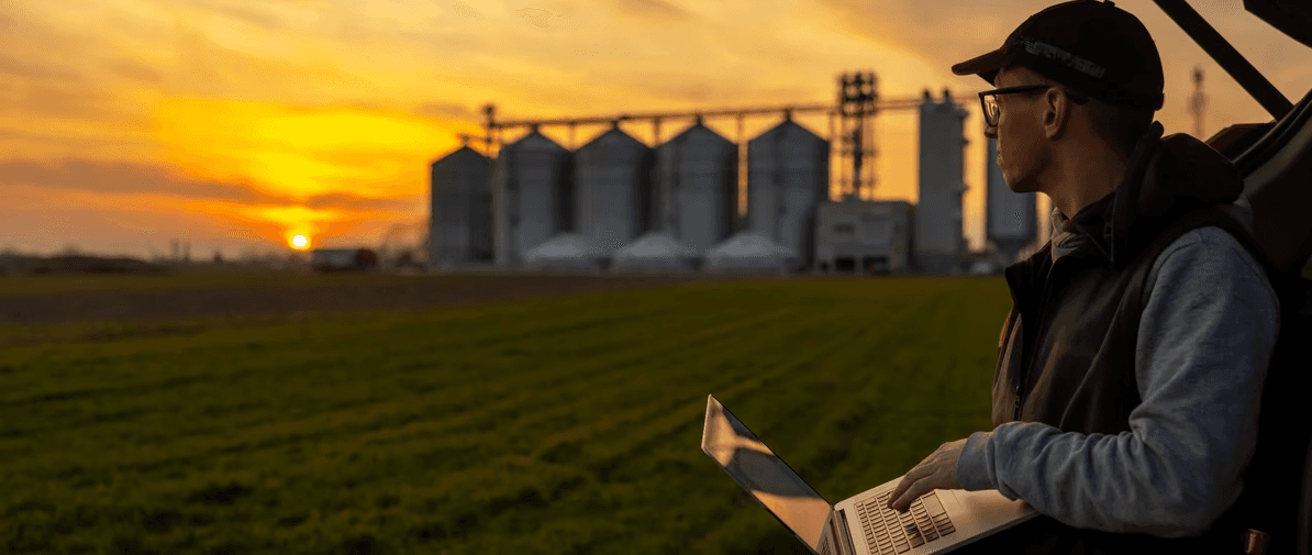 Farmer Working on Laptop in Field at Sunset