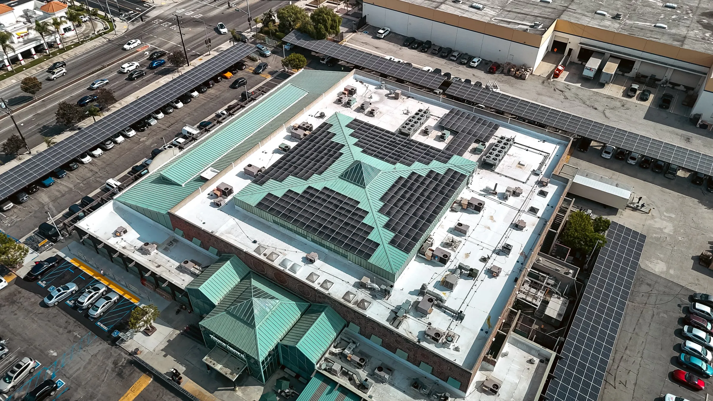 Angled aerial view of a retail center with rooftop solar and a row of solar-covered parking bays