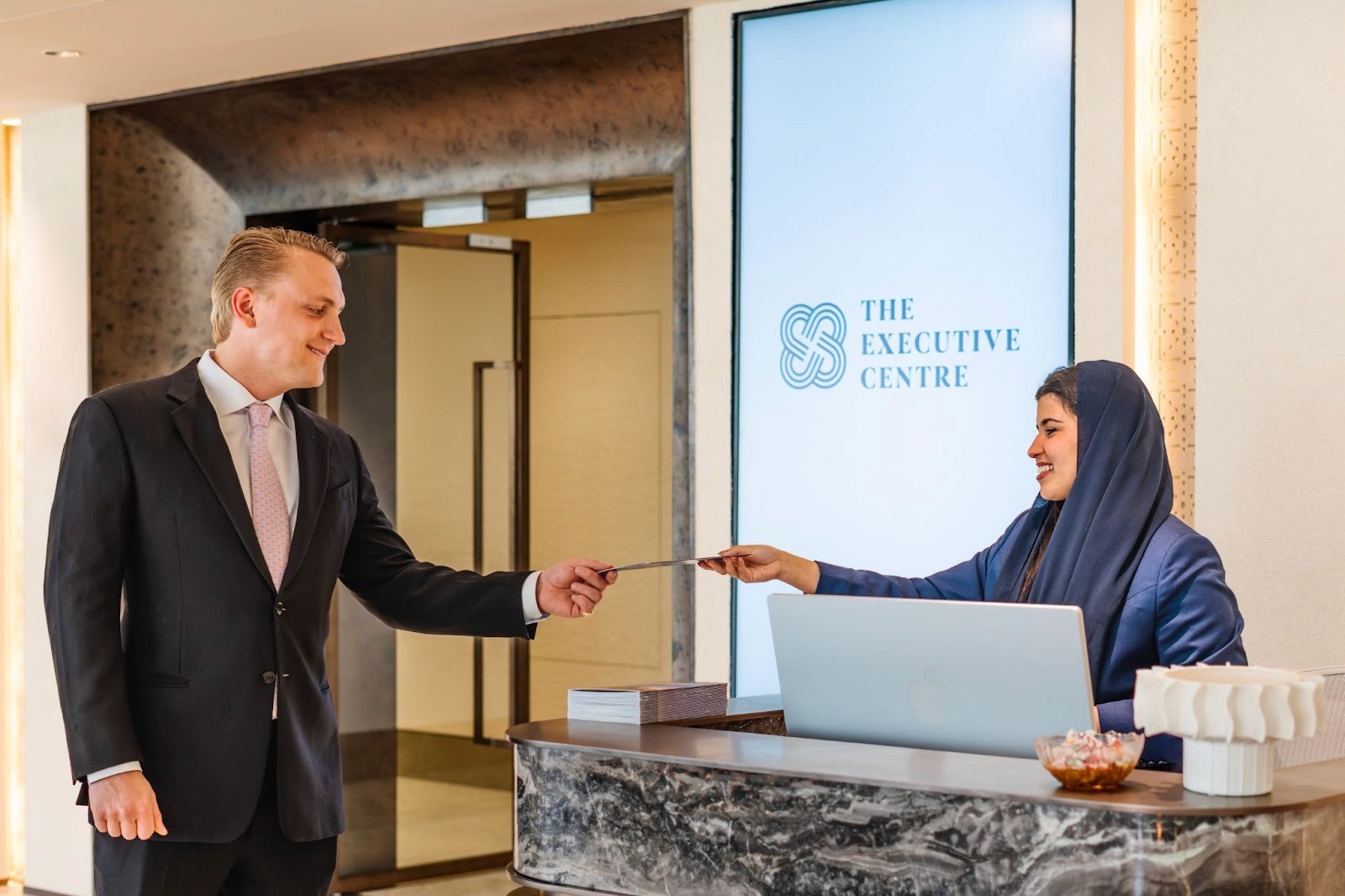 A receptionist at TEC, KAFD Riyadh interacting with a guest. 