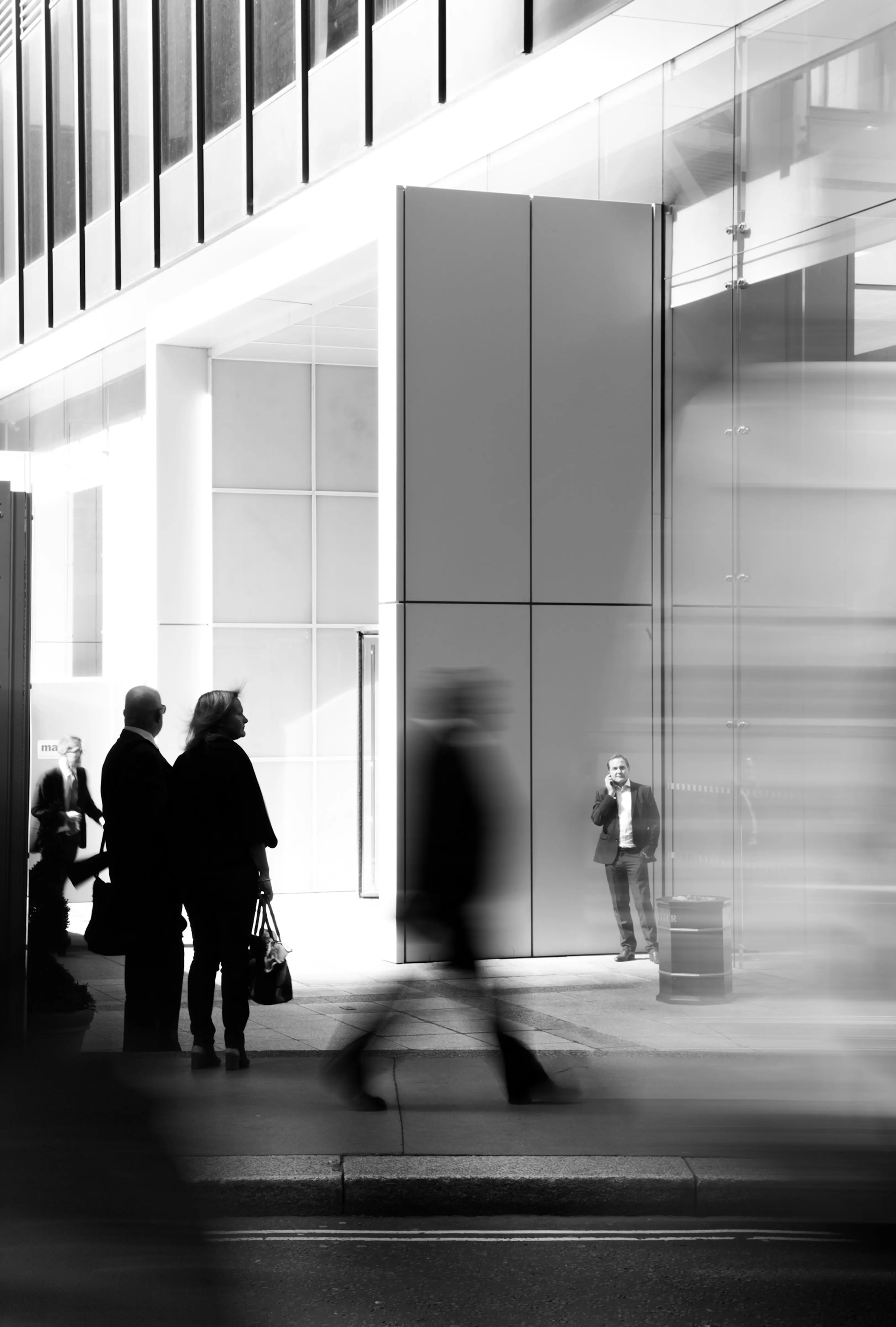 People walking outside a modern glass-fronted office building