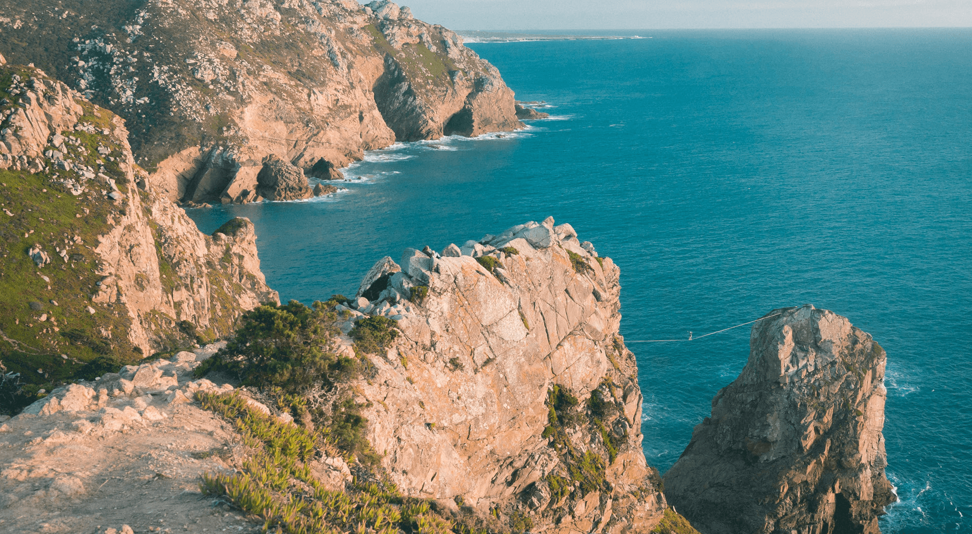 Fine art landscape photography of mountains by the sea coast with a woman practicing slackline