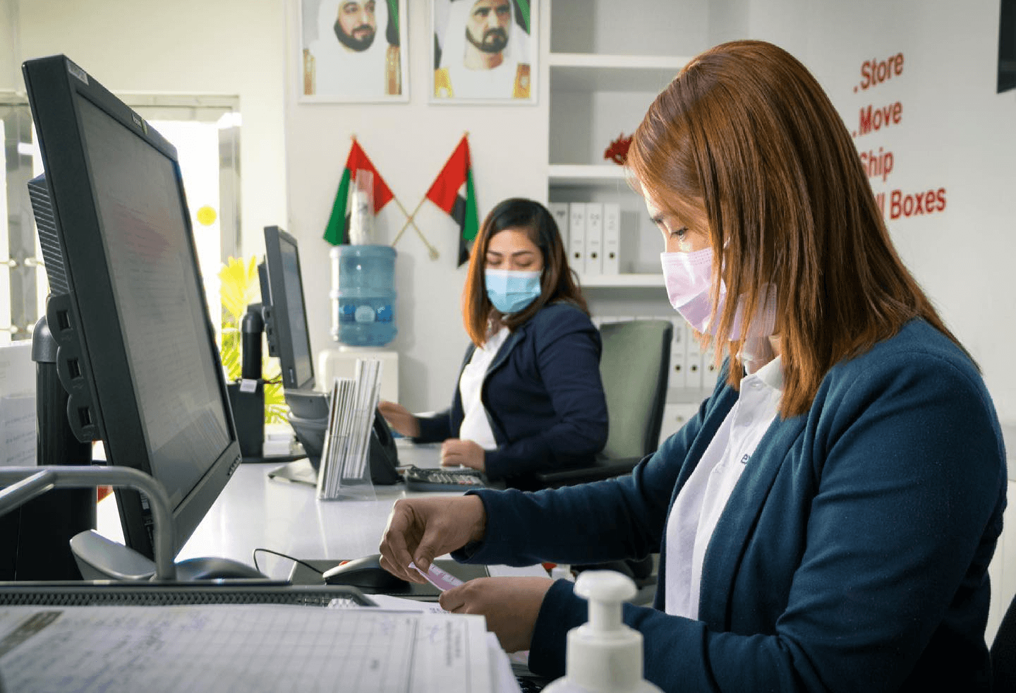 Staff member reviewing customs paperwork at a computer during international shipping clearance in the UAE.&nbsp;