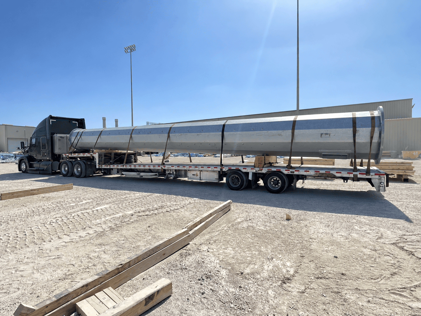 Long industrial pipe secured on a flatbed trailer.