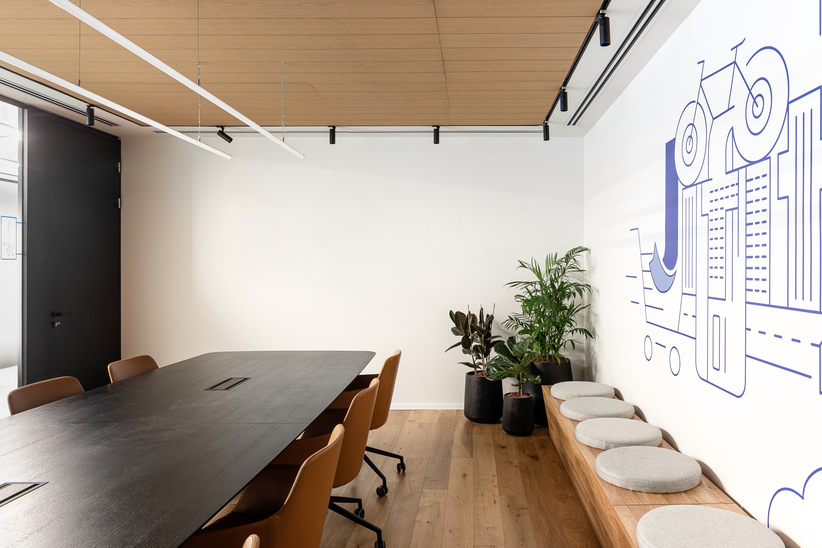 חדר ישיבות ממותג: שילוב גרפיקה ייחודית (Custom Wall Art) המבטאת את צמיחת החברה, עם ריהוט משרדי אלגנטי וצמחייה לרעננות.