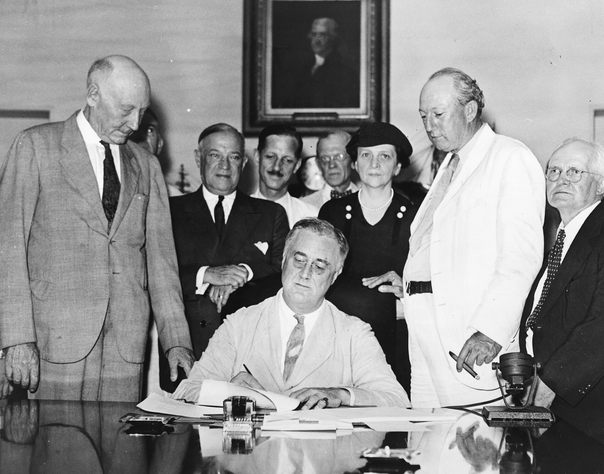Franklin D. Roosevelt seated at a desk with officials