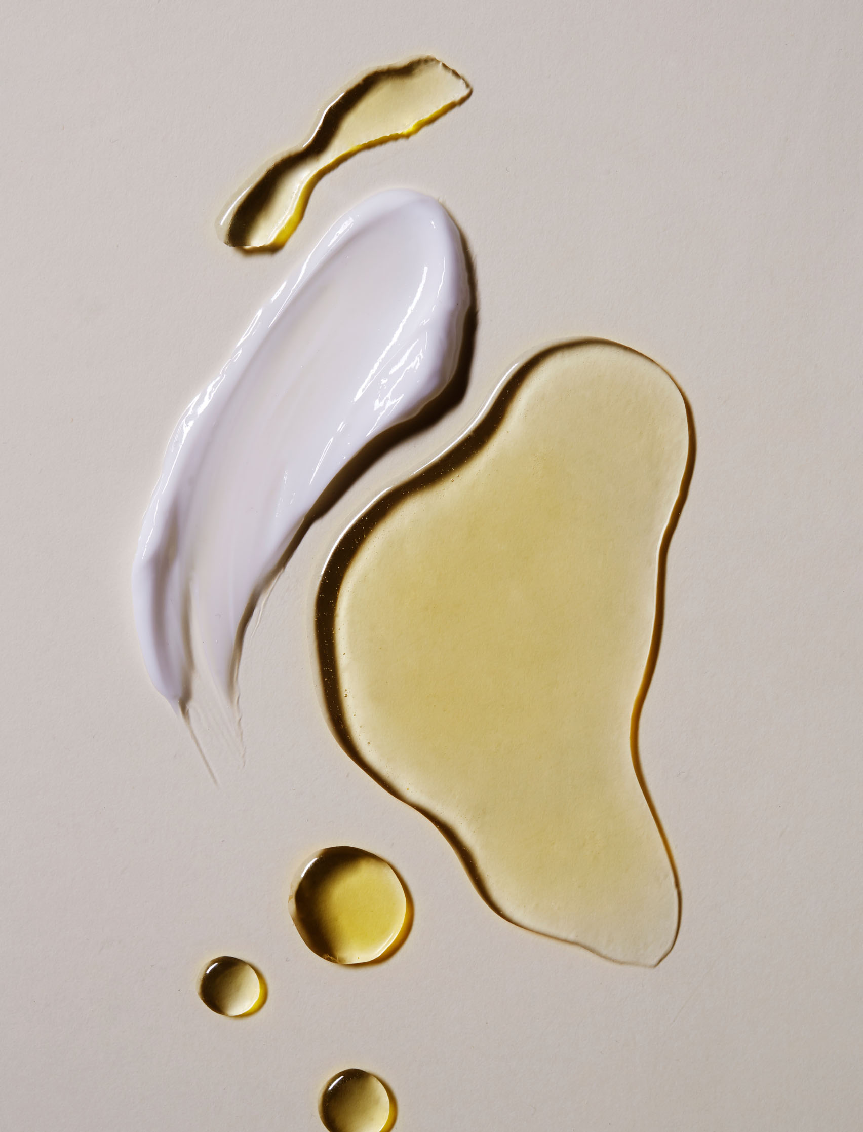 Minimalist product swatches showing the varied textures of Krayna’s creams and oils in shades of white and gold. This product photography highlights the studio's ability to communicate ingredient purity and texture through sophisticated visual storytelling.