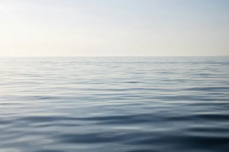 Ruhiger Ozean mit klarem Wasser unter blauem Himmel