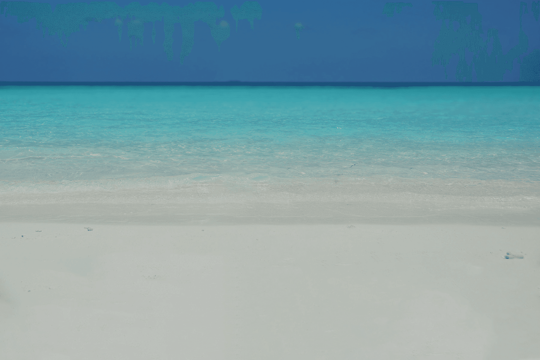 A photo of white sand beach, azure water and blue, clear horizon