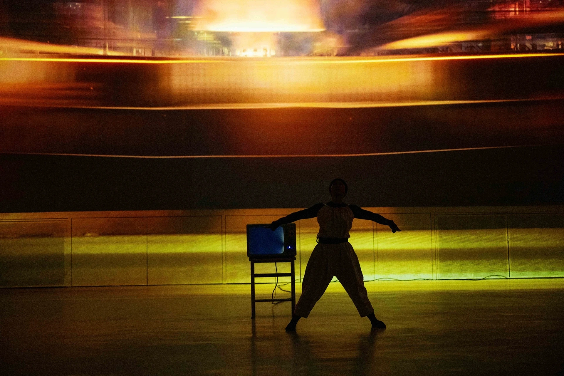 Dancer silhouetted with vintage TV on stool.