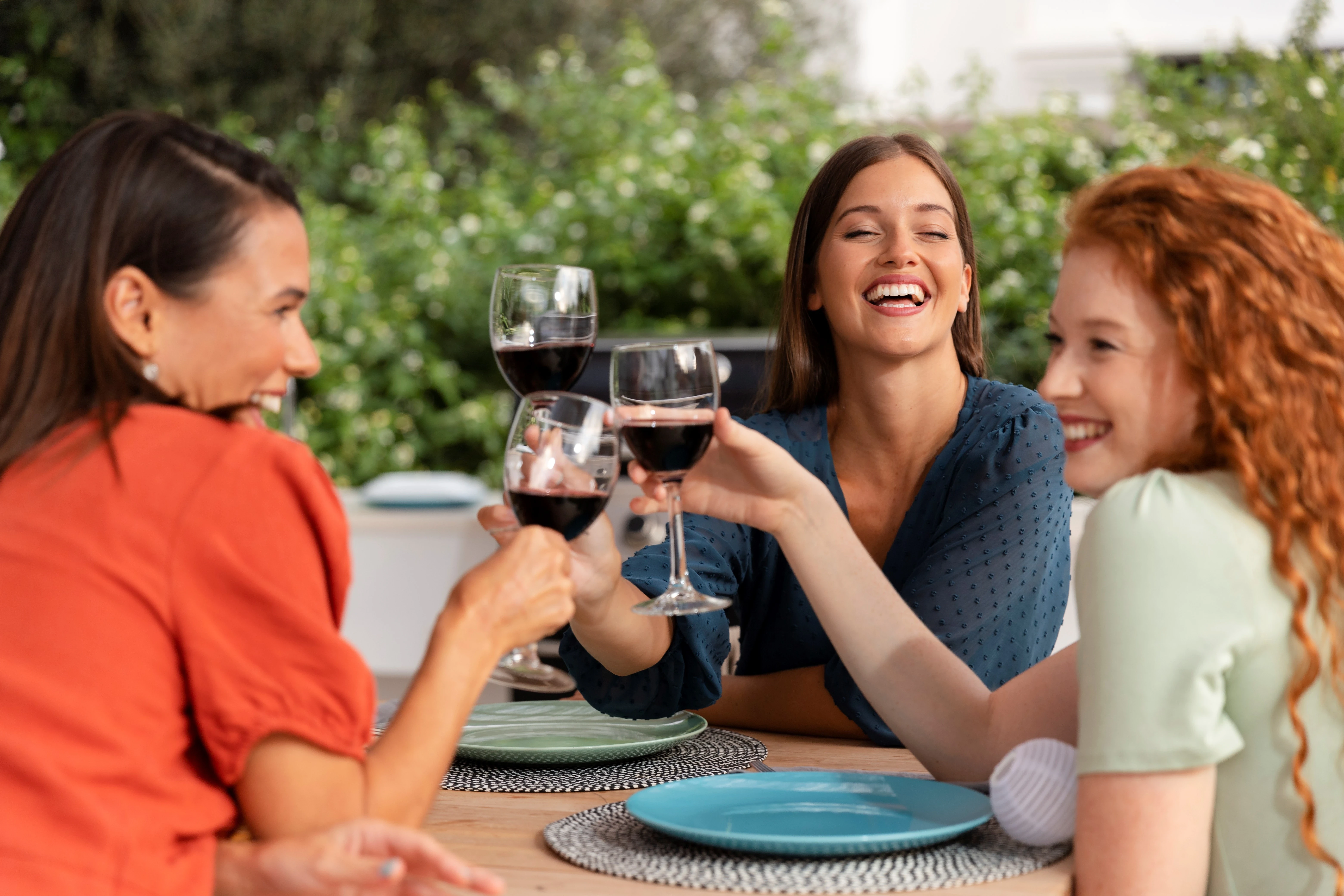 Tres mujeres brindando en una mesa con cerámica al aire libre